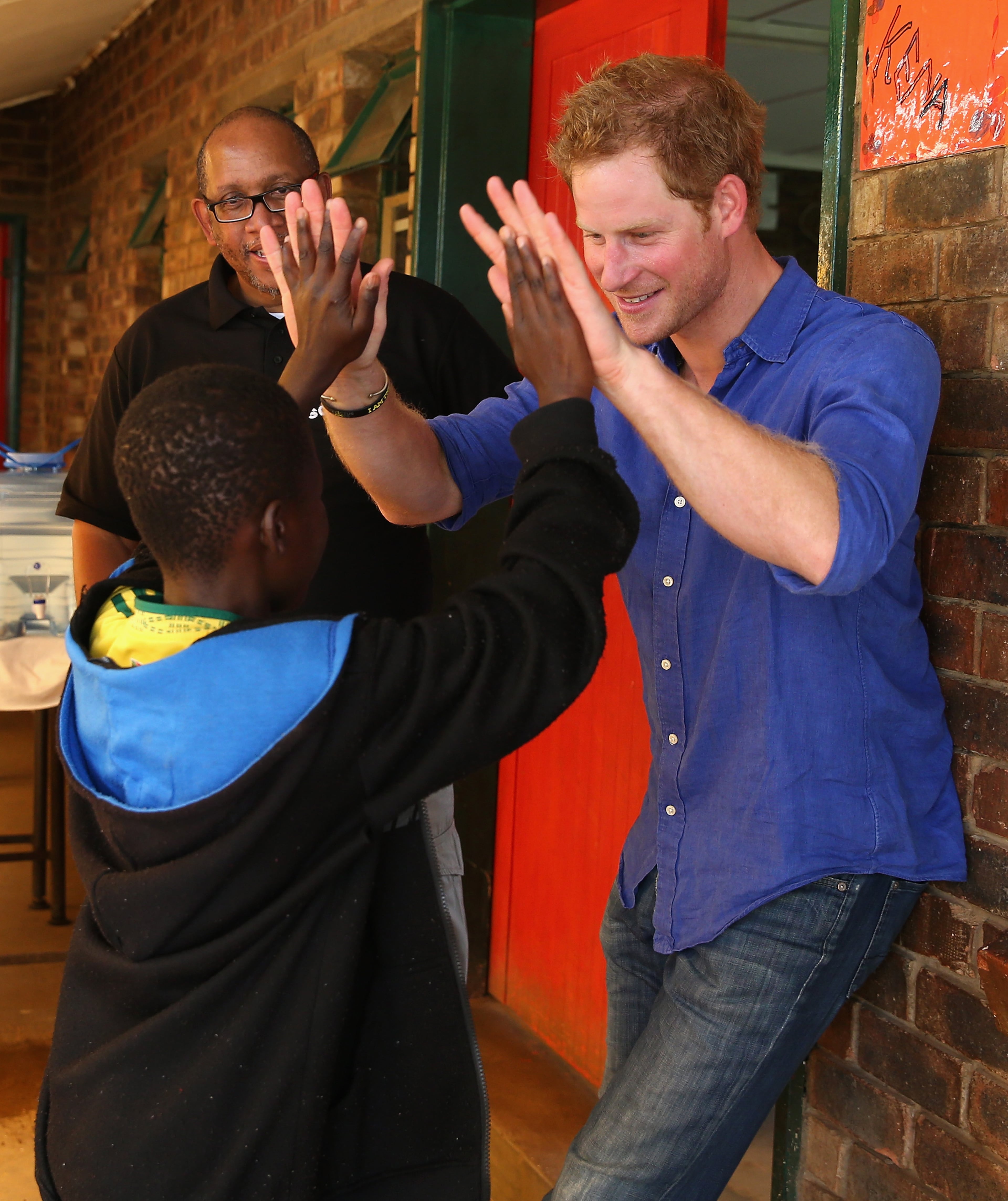 LERIBE, LESOTHO - DECEMBER 09: Prince Harry and Prince Seeiso of Lesotho talk to a child living with HIV during a visit to a Mamohato Network Club for children living with HIV at St Paul Centre on December 9, 2014 in Maseru, Lesotho. Prince Harry was visiting Lesotho to see the work of his charity Sentebale. Sentebale provides healthcare and education to vulnerable children in Lesotho, Southern Africa. The particular theme of his visit was to check on the progress of the Mamohato Childrens Centre which will provide vital support to children affected by HIV. Prince Harry founded Sentebale (which means Forget Me Not in Sesotho) with Prince Seeiso in 2006. (Photo by Chris Jackson/Getty Images for Sentebale)