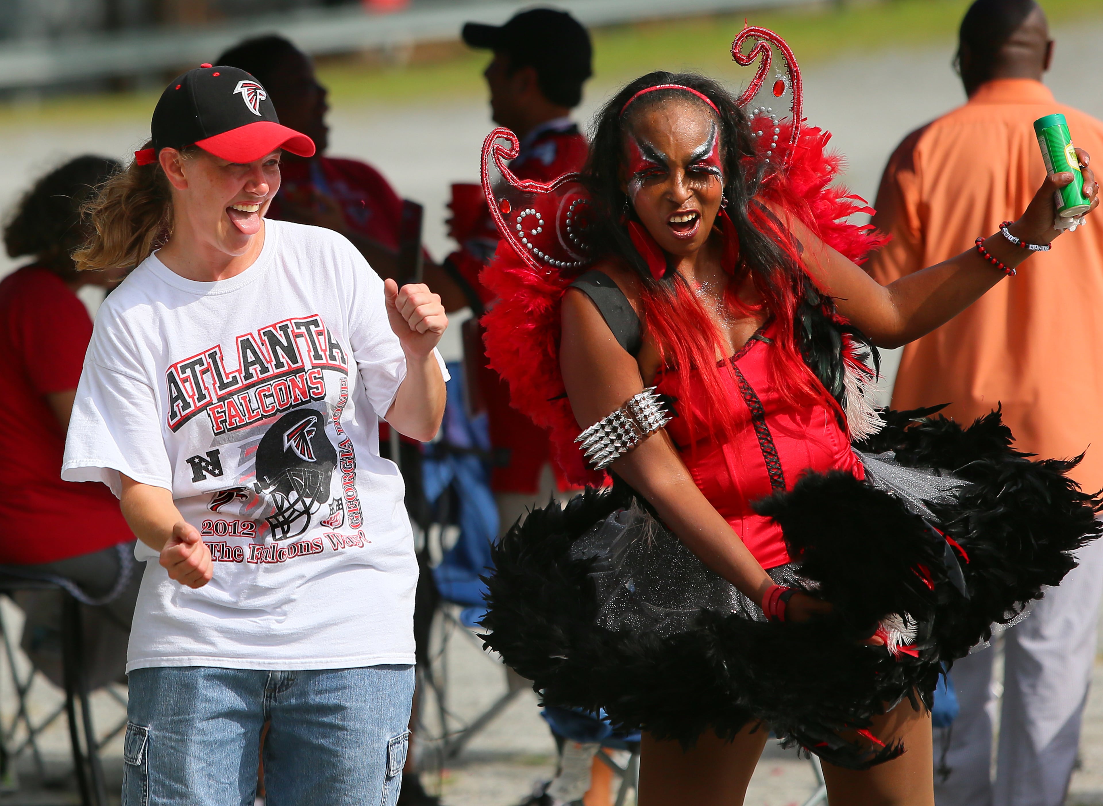 Members of "The Nest" tailgators Amy Moody (left) and Carolyn Freeman (right), "The Original Bird Lady," dance in the parking lot while tailgating before the Falcons NFL exhibition game against the Cincinnati Bengals on Thursday, Aug. 8, 2013, in Atlanta.