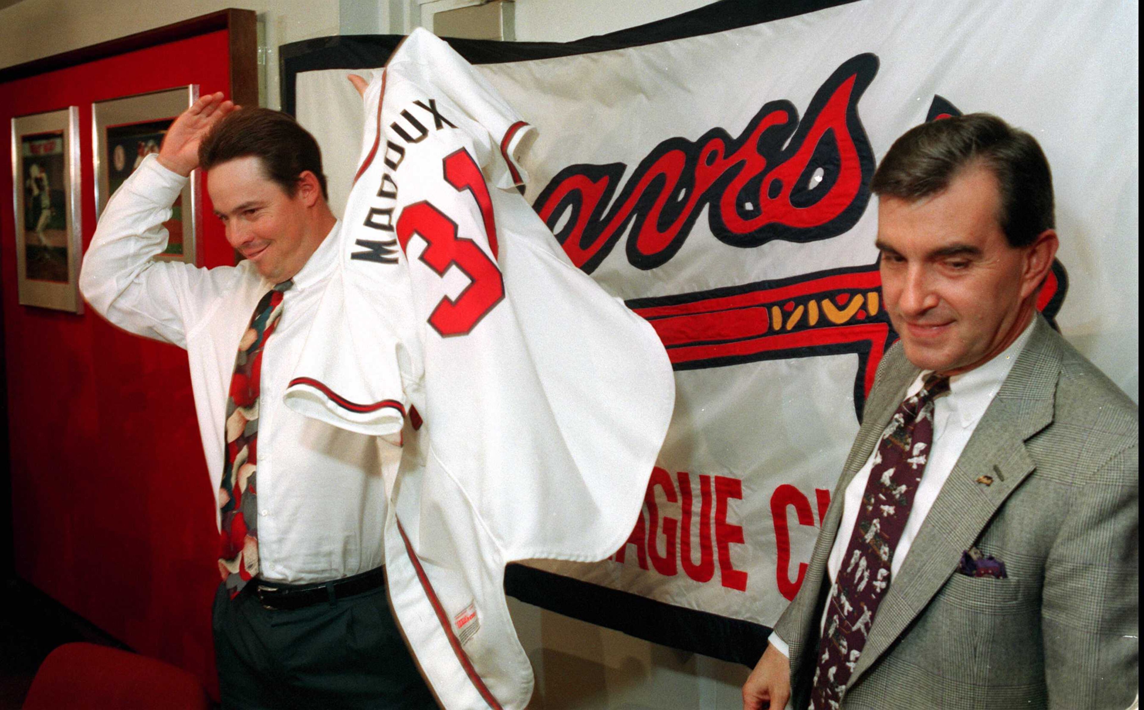 After signing as a free agent, Greg Maddux tries on his new Braves jersey on Dec. 15, 1992 at a press conference with Braves general manager John Schuerholz.