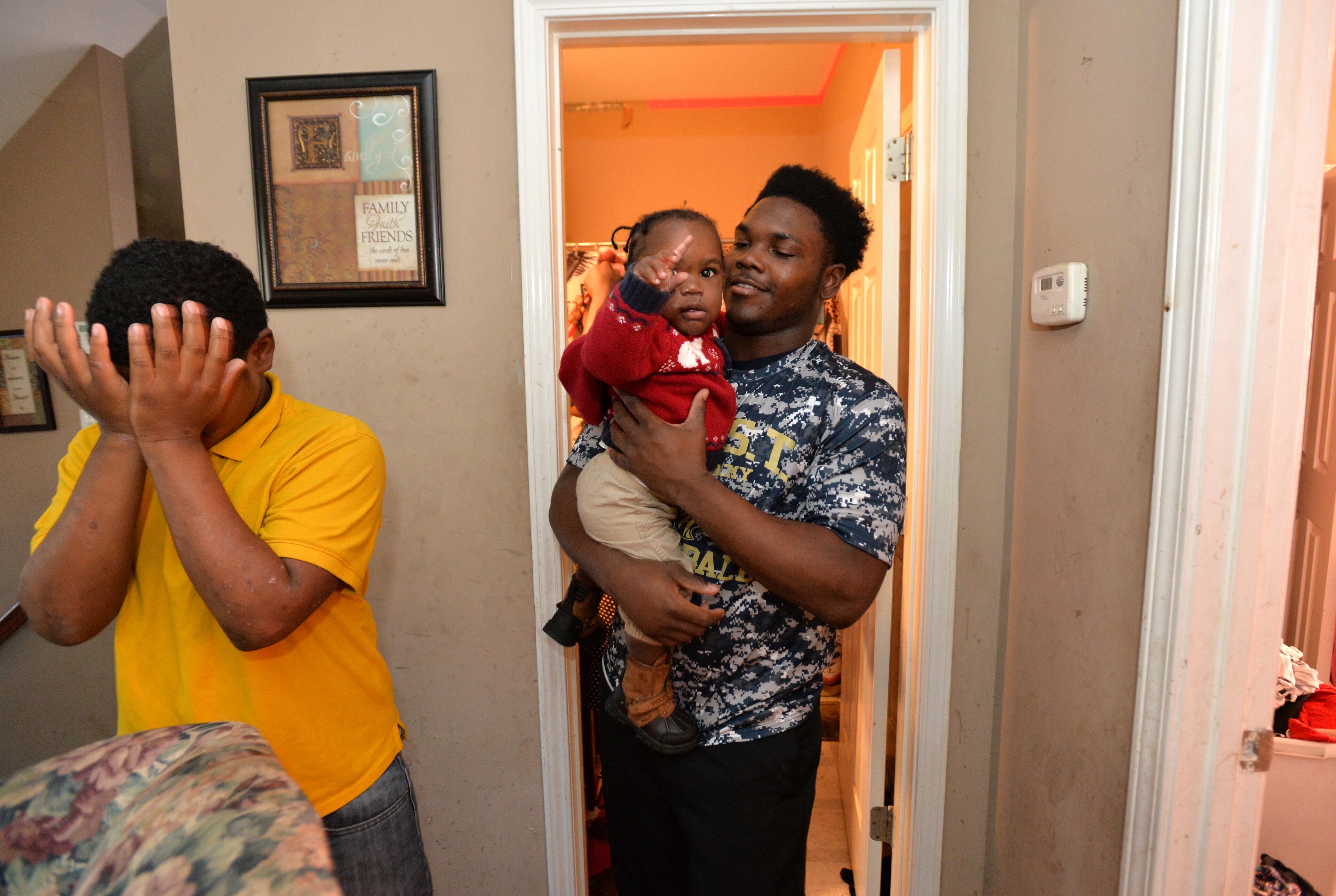 Darius Marshall, 18, holds his nephew Demetrius Broadnax Jr., 1, as he and his brother Dazmine (left), 12, get ready to go to church at their home on Sunday morning. HYOSUB SHIN / HSHIN@AJC.COM
