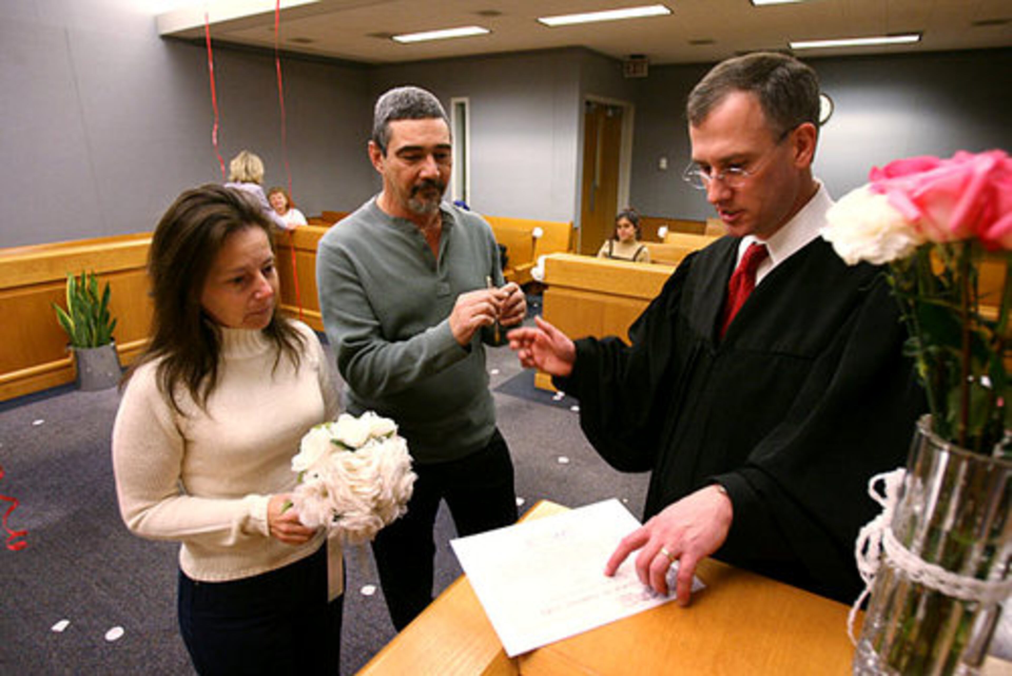Wendy Gottlieb (left) and Randy Gottlieb, her husband of nearly 25 years, listen as Gwinnett County Chief Migistrate George Hutchinson, III, instructs them where to sign on the form commemorating the renewal of ther marriage vows. The Gottliebs will celebrate their 25th anniversary later this month on February 19.