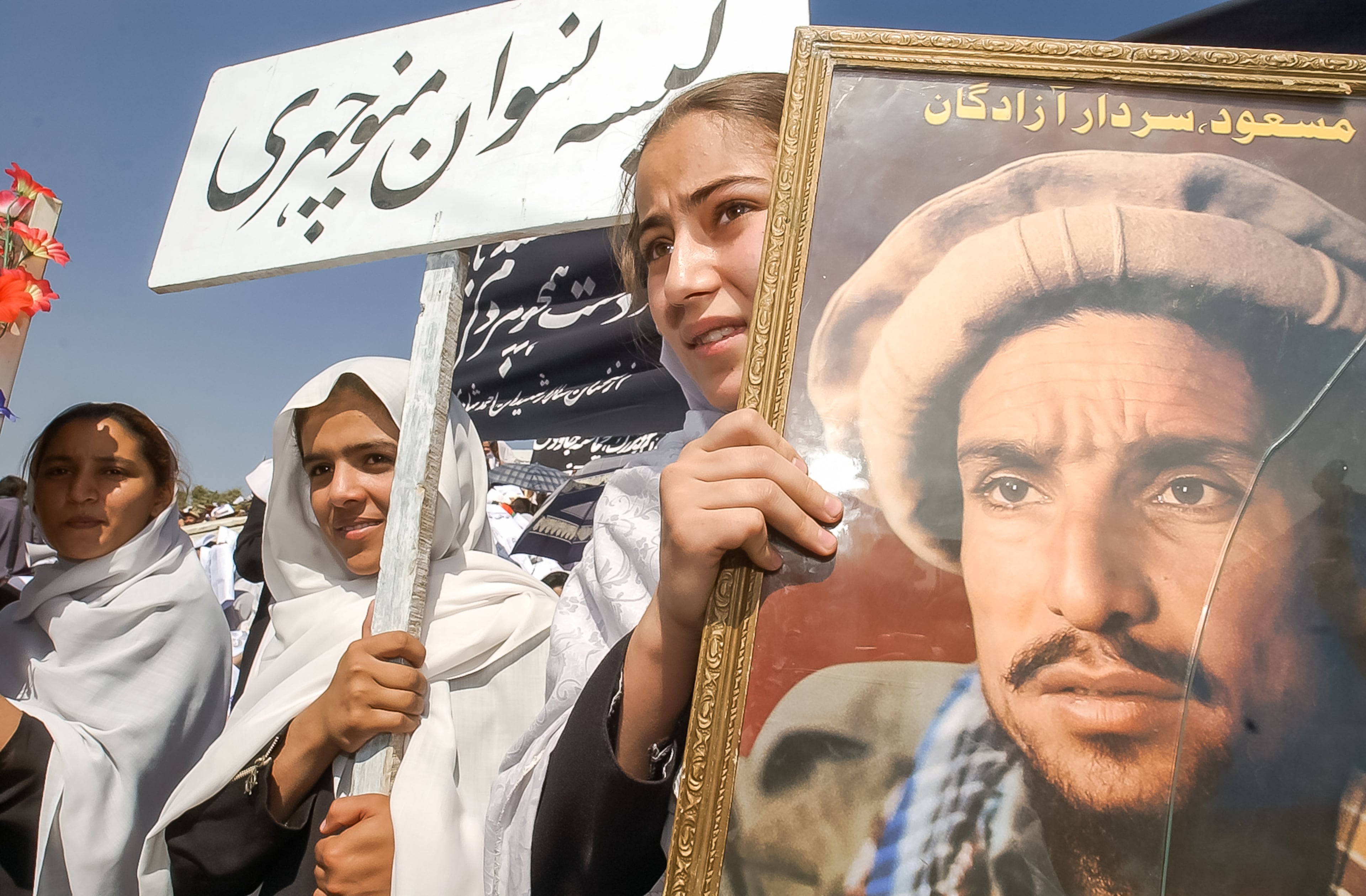 KABUL, AFGHANISTAN: Students from the Naswan Manochary girls' school hold a poster of Ahmad Shah Masoud outside Ghazi Stadium in Kabul Monday, Sept. 9, 2002. Inside, a commemoration ceremony took place for the year anniversary of the assassination Masoud, who was a popular Afghan Tajik rebel leader who fought against the Soviets and the Taliban. He was killed on September 9, 2001, by two Arabs posing as journalists wishing to interview him. (Bita Honarvar / The Atlanta Journal-Constitution)