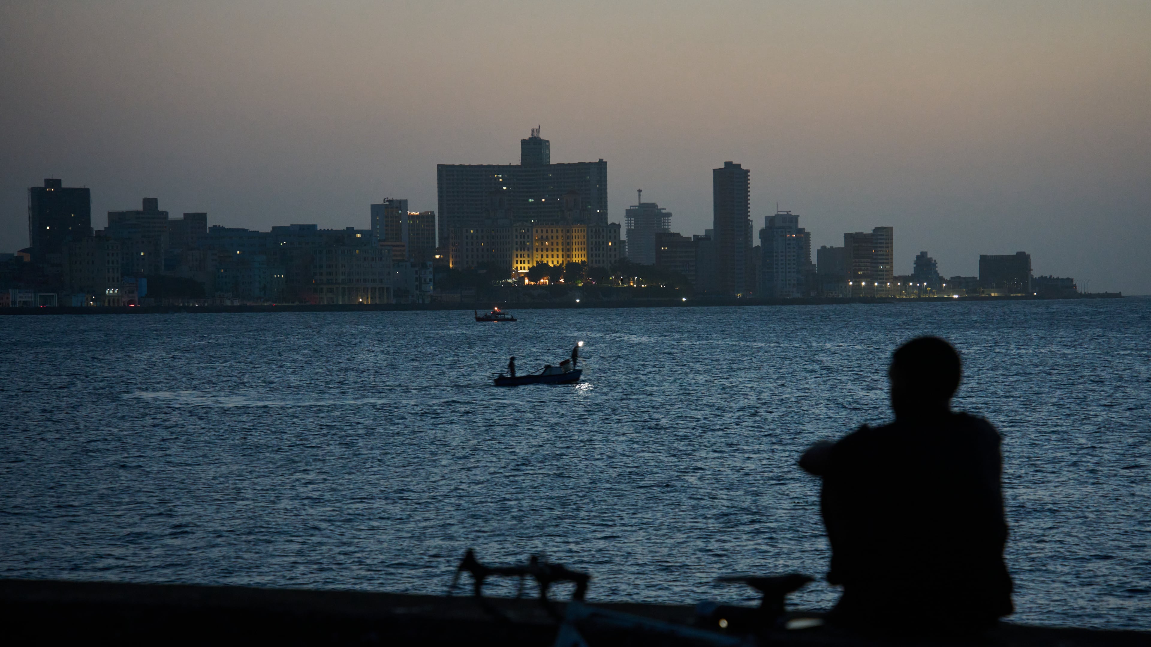 A man sits on the Malecón seawall after sunset during a blackout in Havana, Cuba, Tuesday, July 14, 2026. (AP Photo/Ramon Espinosa)