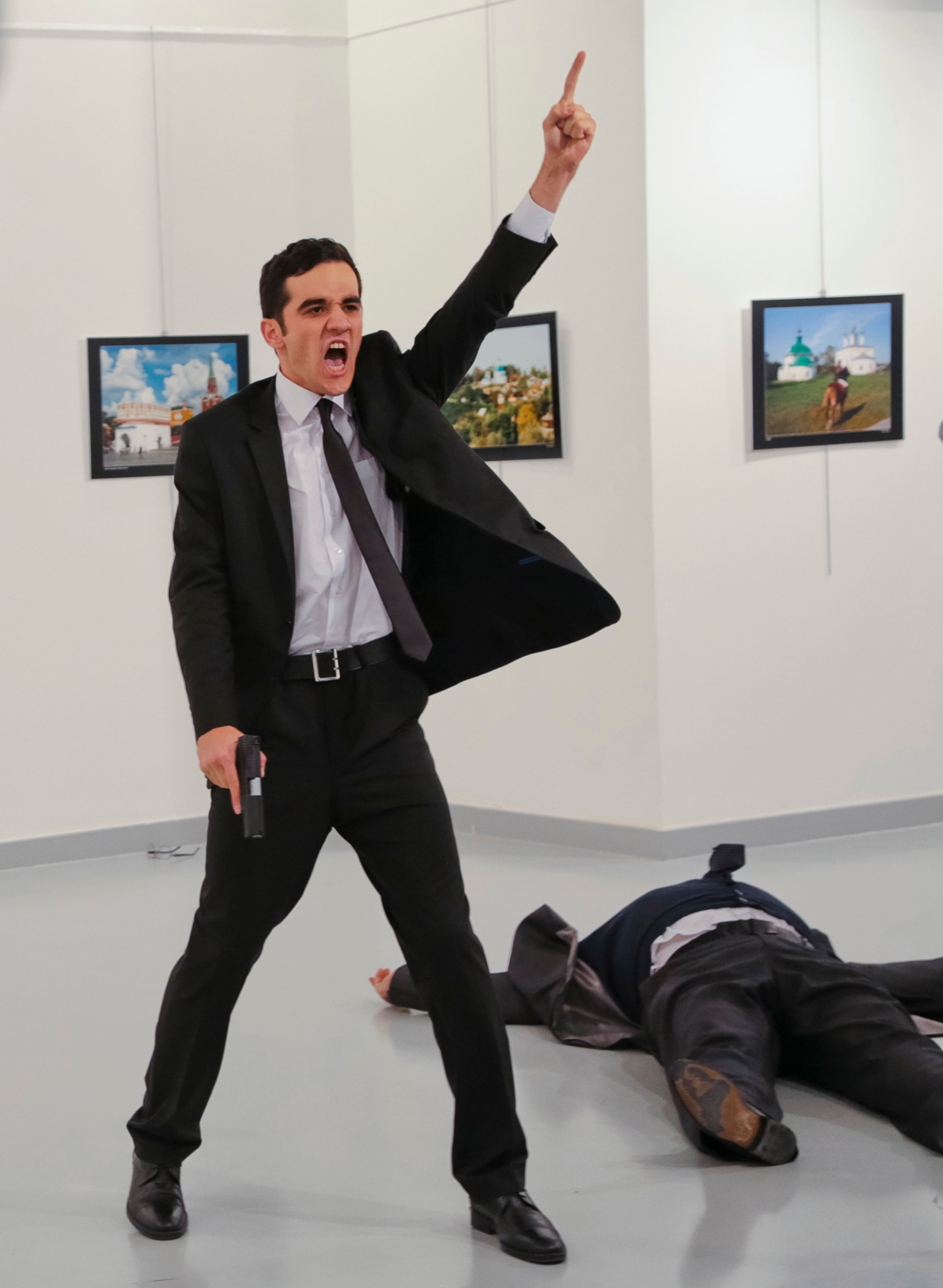 An unnamed gunman gestures after shooting the Russian Ambassador to Turkey, Andrei Karlov, at a photo gallery in Ankara, Turkey, Monday, Dec. 19, 2016. A gunman opened fire on Russia's ambassador to Turkey at a photo exhibition on Monday. The Russian foreign ministry spokeswoman said he was hospitalized with a gunshot wound. (AP Photo/Burhan Ozbilici)