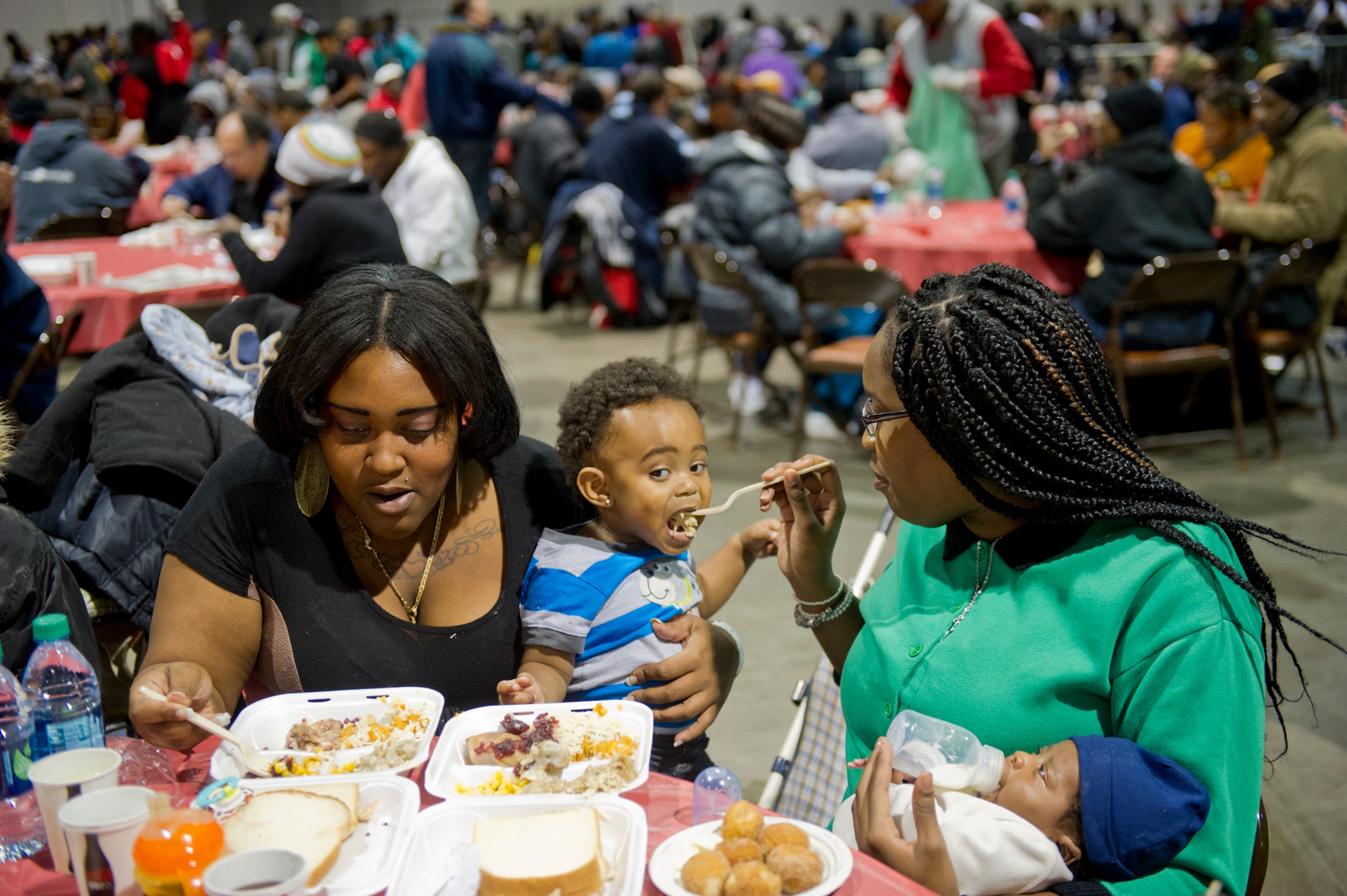 Jonaua Hodge (right) holds her son Malachi as she feeds Javion Flowers while her sister Jacquee Hodge eats a five course Thanksgiving meal during the Hosea Feed the Hungry and Homeless annual Thanksgiving meal at the Georgia World Congress Center in Atlanta on Nov. 28, 2013.