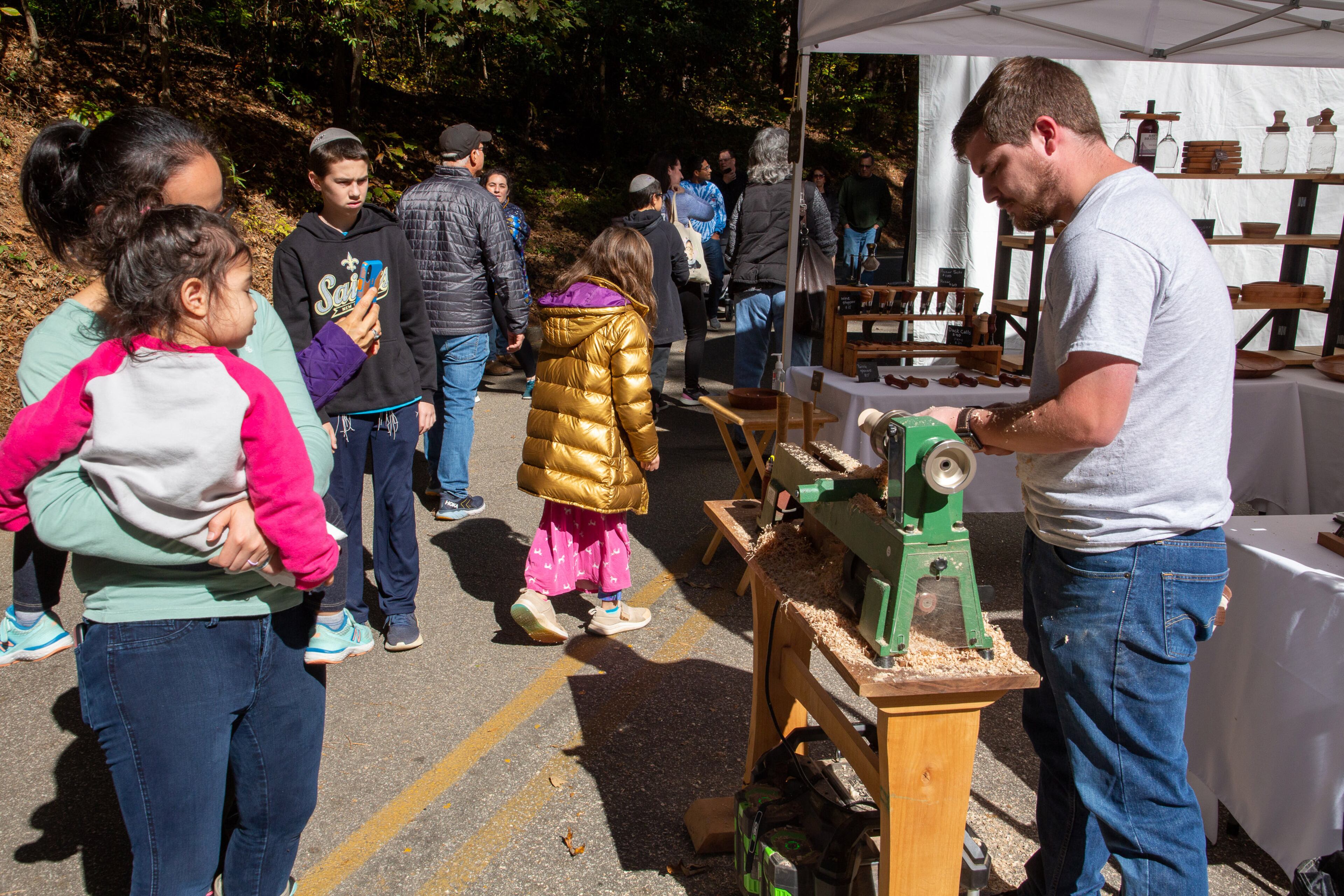 Cody Garrard turns wooden tops in front of his artist tent during the Chastain Park Fall Arts Festival on Sunday, November 7, 2021. STEVE SCHAEFER FOR THE ATLANTA JOURNAL-CONSTITUTION