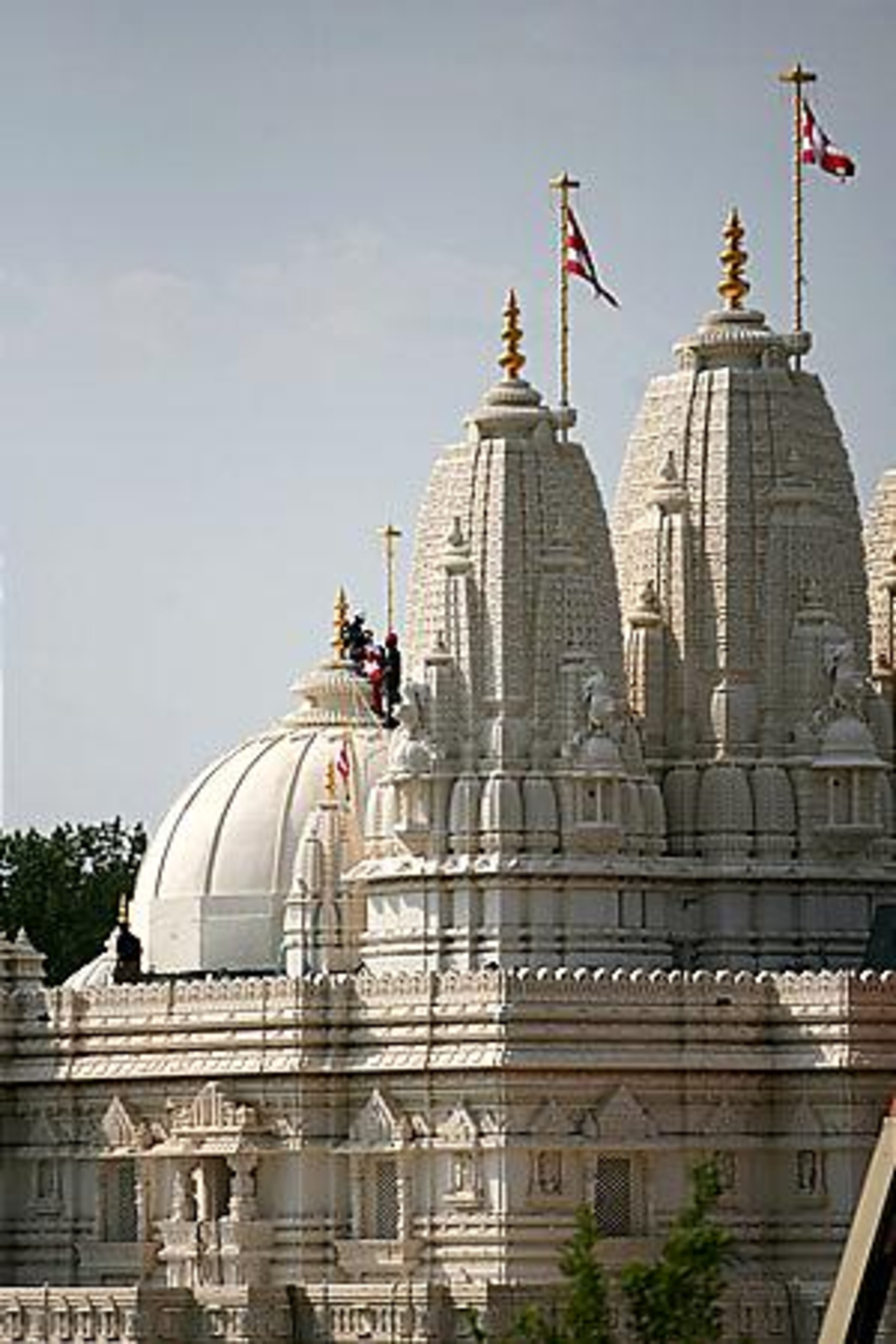 Volunteers prepare to put flags on each dome at the new Hindu temple before the grand procession Saturday. Tens of thousands of Hindus are expected Sunday to hear the sect's guru, His Holiness Pramukh Swami Maharaj, bless the $19 million structure.