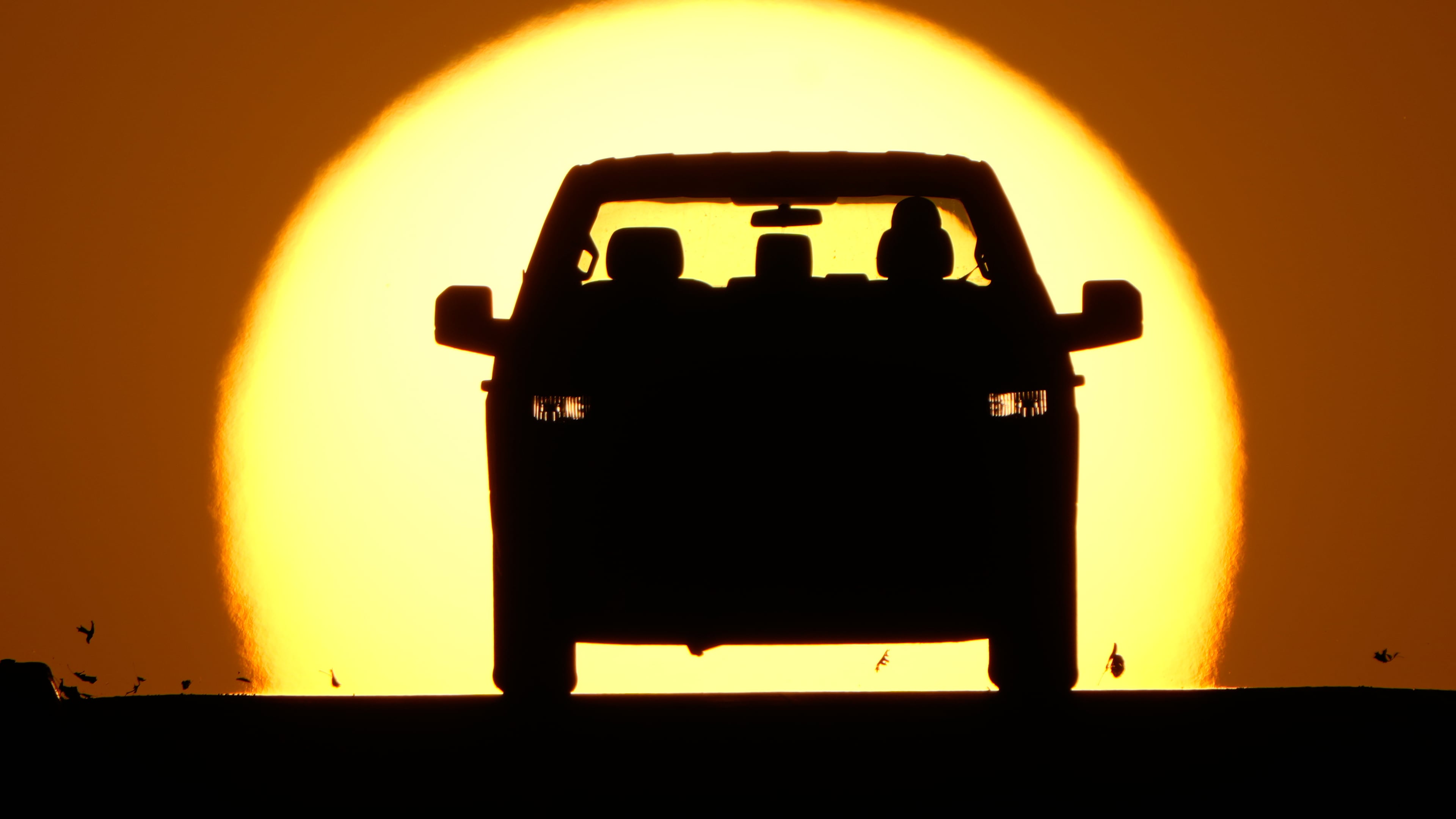 FILE - A motorist is silhouetted by the setting sun March 26, 2026, in Lenexa, Kan. (AP Photo/Charlie Riedel)