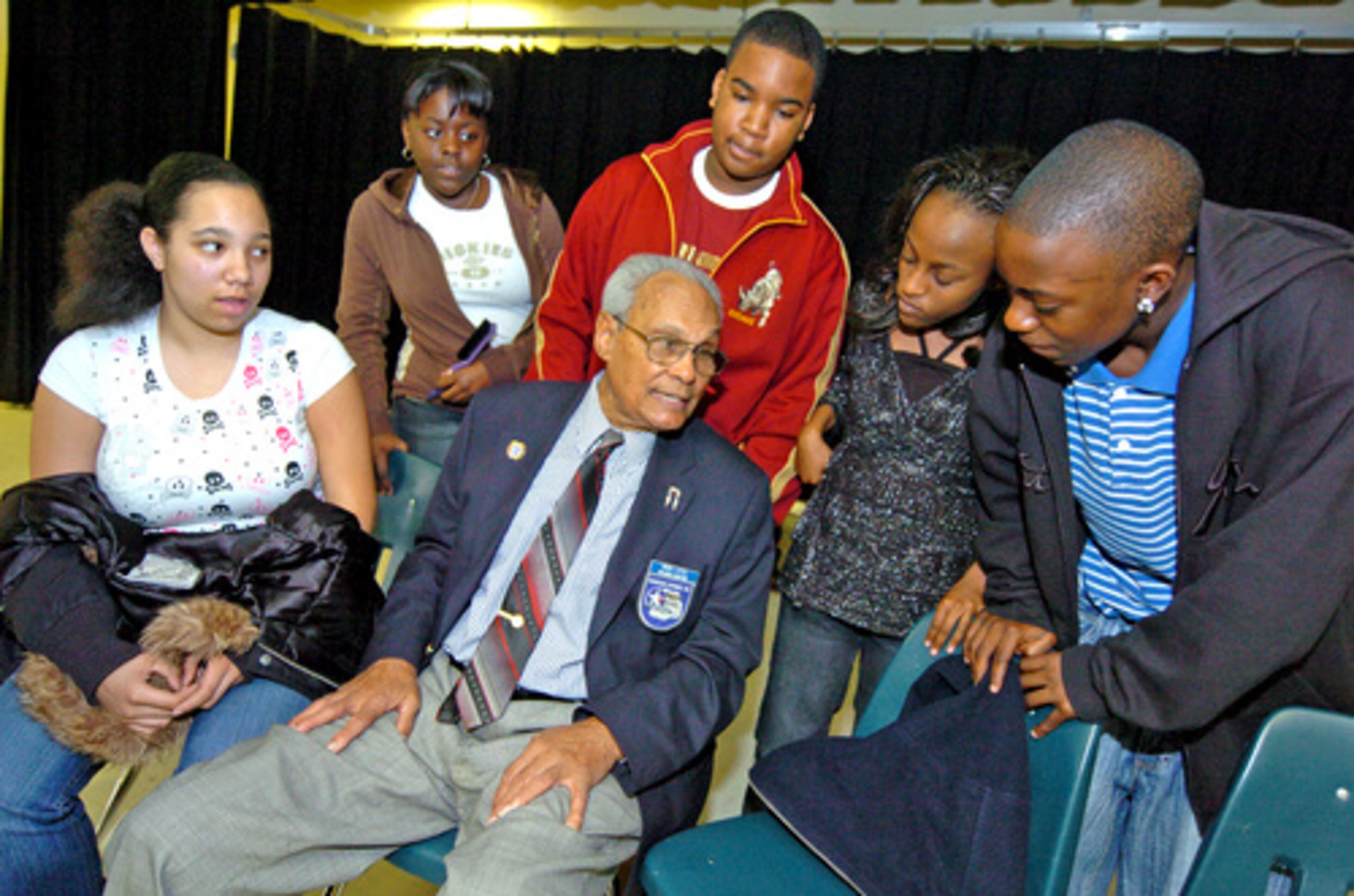 Flight Officer Hiram Little, a former Tuskegee Airman, is surrounded by students asking questions (from left) Stephanie Brown, Erin Alderson, Torrey Prescod, Zoe Maddox and Danatolo Dunn, all 8th graders at Shamrock Middle School. The airmen were the first African-Americans to be trained to fly in U.S. armed forces -- and they shattered racial stereotypes.