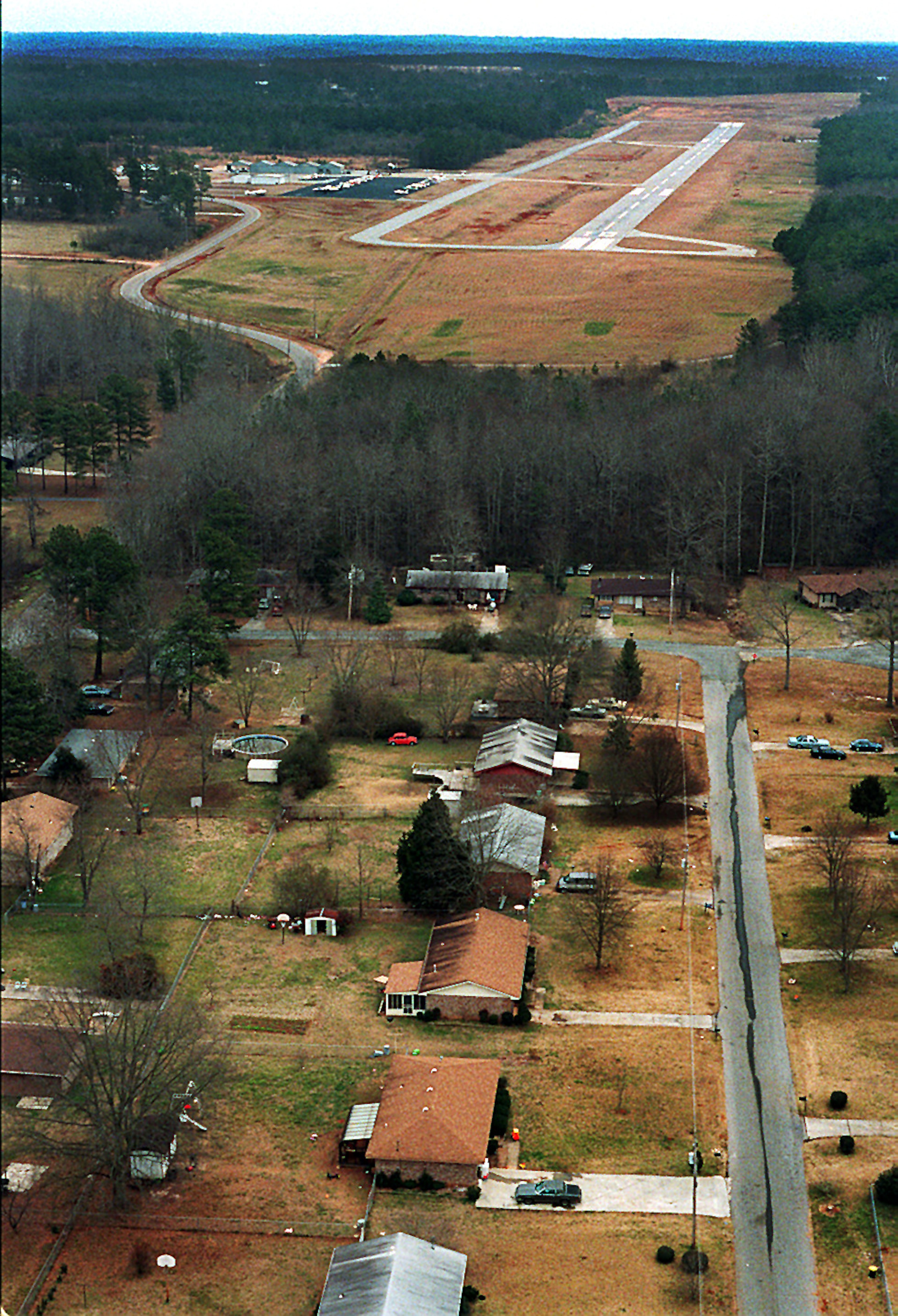 The runway of the Newton County Airport and a subdivision off Richardson Street are separated only by a small patch of woods as seen in this aerial photograph taken on February 14, 1995.
