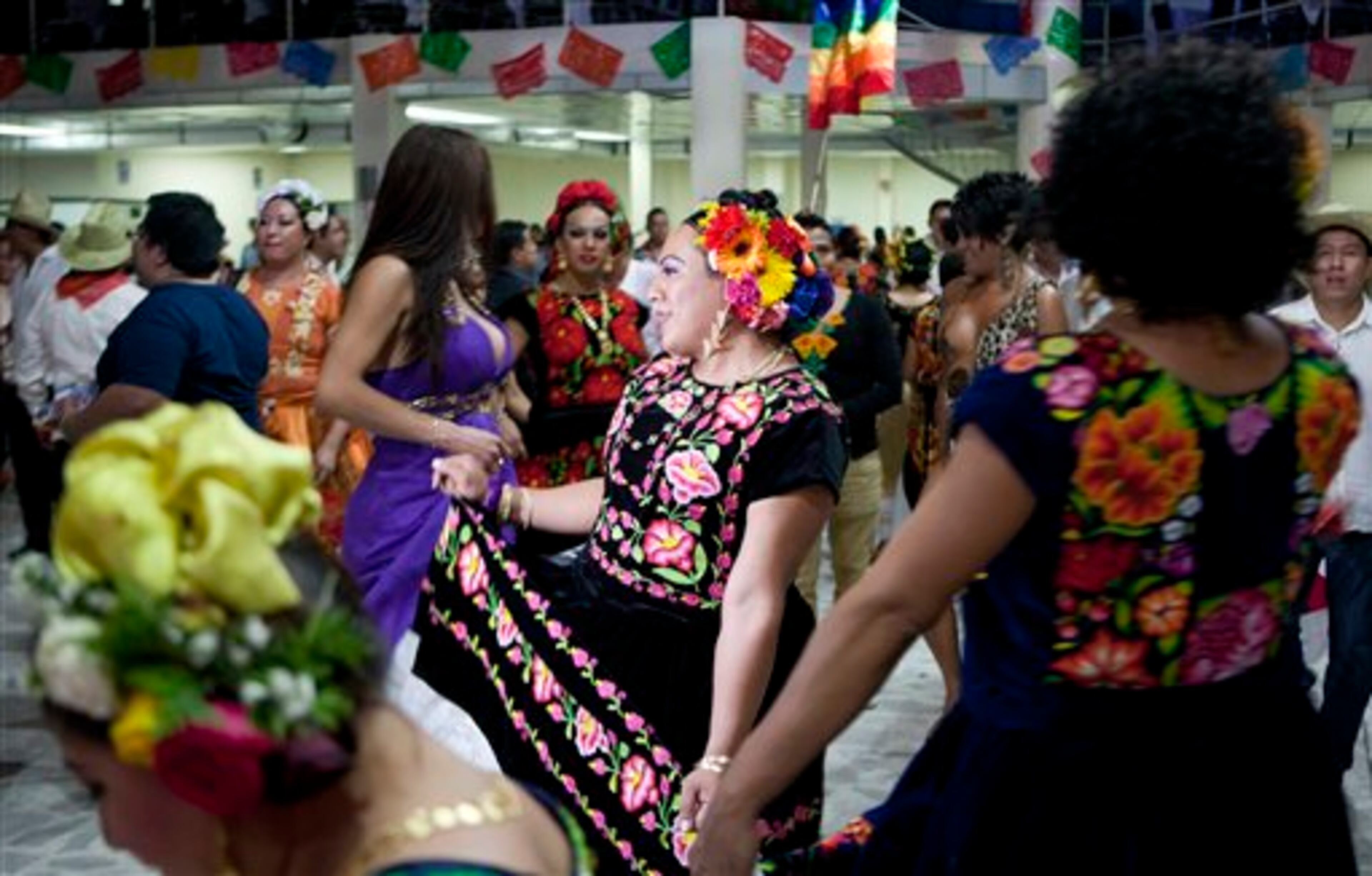 In this June 29, 2013 photo, muxes, as Zapotec indigenous men who dress and behave in ways associated with women are known, gather for a party in Mexico City. Muxes, (pronounced MOO-shays) living in Mexico City gathered to share their traditions at a community party or "vela," as the event is called in their hometown Juchitan, a city of Zapotecs in the southern state of Oaxaca. A cumbia band played while the singer invited people sitting and talking at tables packed with food and drinks to dance. (AP Photo/Eduardo Verdugo)