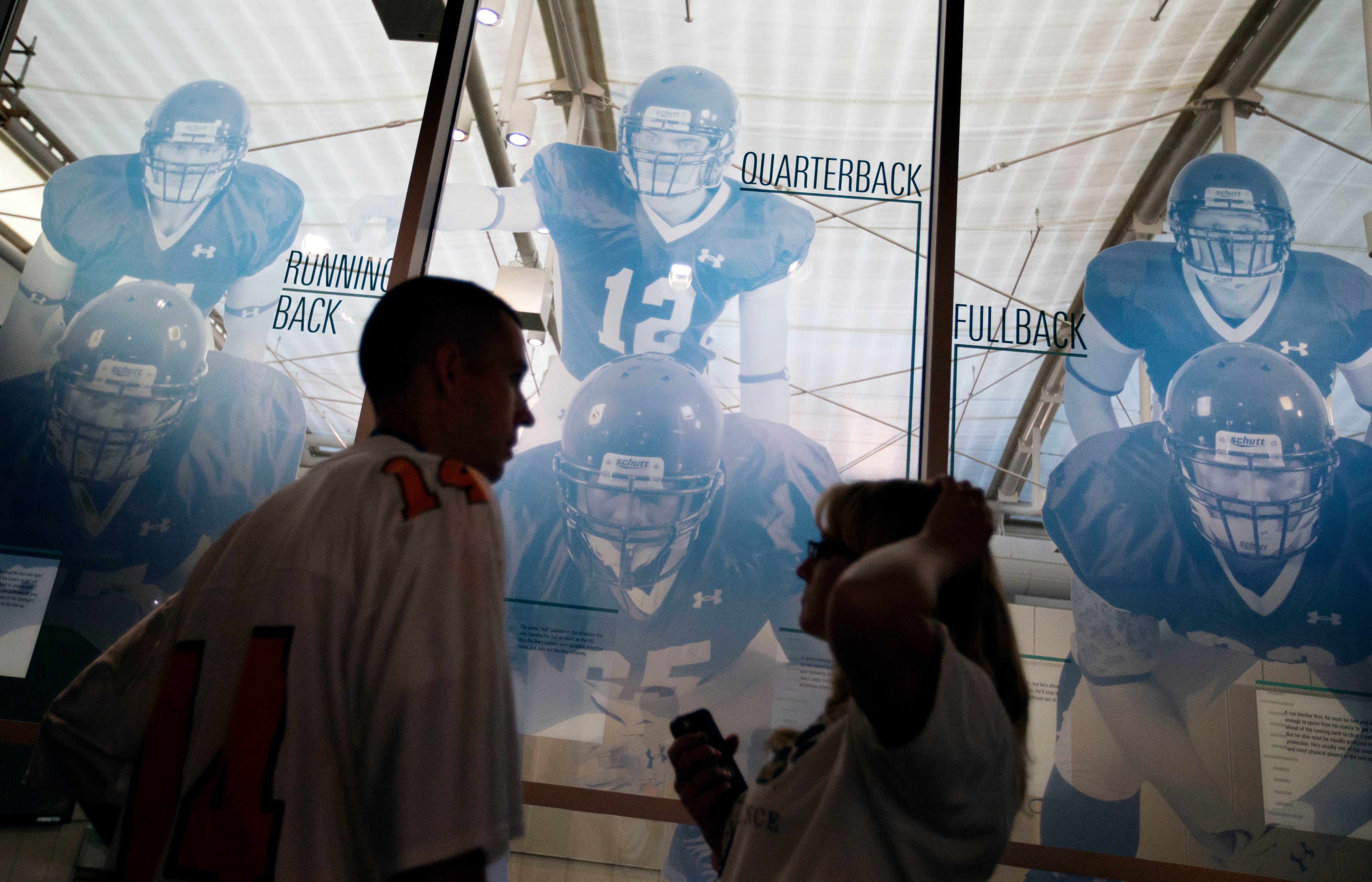 Visitors tour the College Football Hall of Fame before spending the night, Wednesday, Aug. 13, 2014, in Atlanta. One hundred contest winners who wrote an essay detailing their love of college football were selected to stay with a guest overnight in Atlanta's College Football Hall of Fame before its grand opening and win a year's supply of Chick-fil-A. The crowd of 200 who came from as far away as Hawaii were among the first to experience the College Football Hall of Fame and Chick-fil-A Fan experience before it opens to the public on Aug. 23. After touring the exhibits guest were served dinner on the football field before pitching their tents on the turf and settling in for the night as college football themed movies such as "Rudy" were played on the jumbotron. The hall was previously located in South Bend, Indiana, but was plagued by poor attendance. (AP Photo/David Goldman)