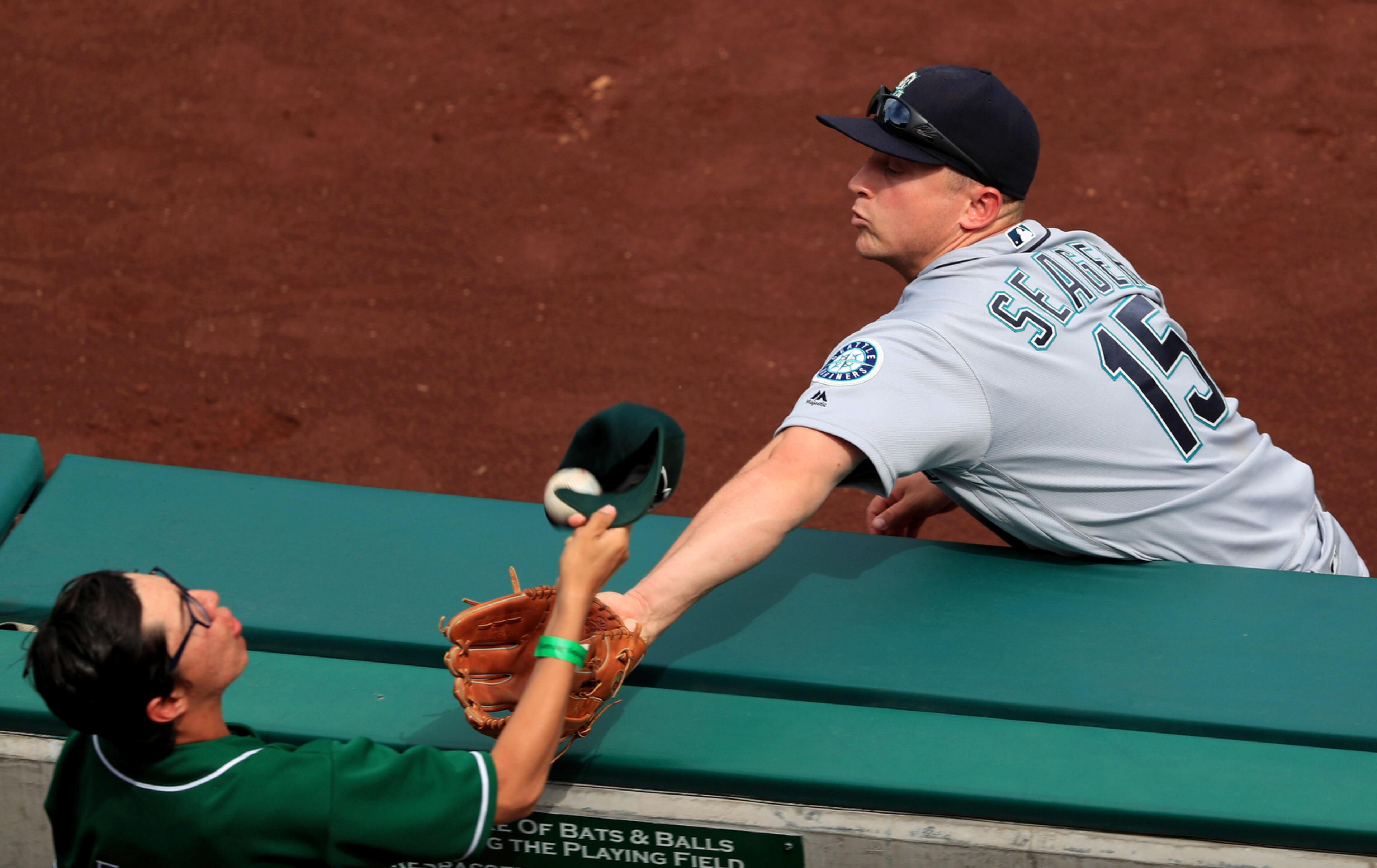 HAT TRICK--ANAHEIM, CA - APRIL 24: Kyle Seager #15 of the the Seattle Mariners is unable to reach a foul ball hit by Mike Trout #27 of the the Los Angeles Angels of Anaheim as a fan tries to catch it with his hat during the eighth inning of a baseball game between the Los Angeles Angels of Anaheim and the Seattle Mariners at Angel Stadium of Anaheim on April 24, 2016 in Anaheim, California. The Seattle Mariners defeated the Los Angeles Angels of Anaheim 9-4. (Photo by Sean M. Haffey/Getty Images) *** BESTPIX ***