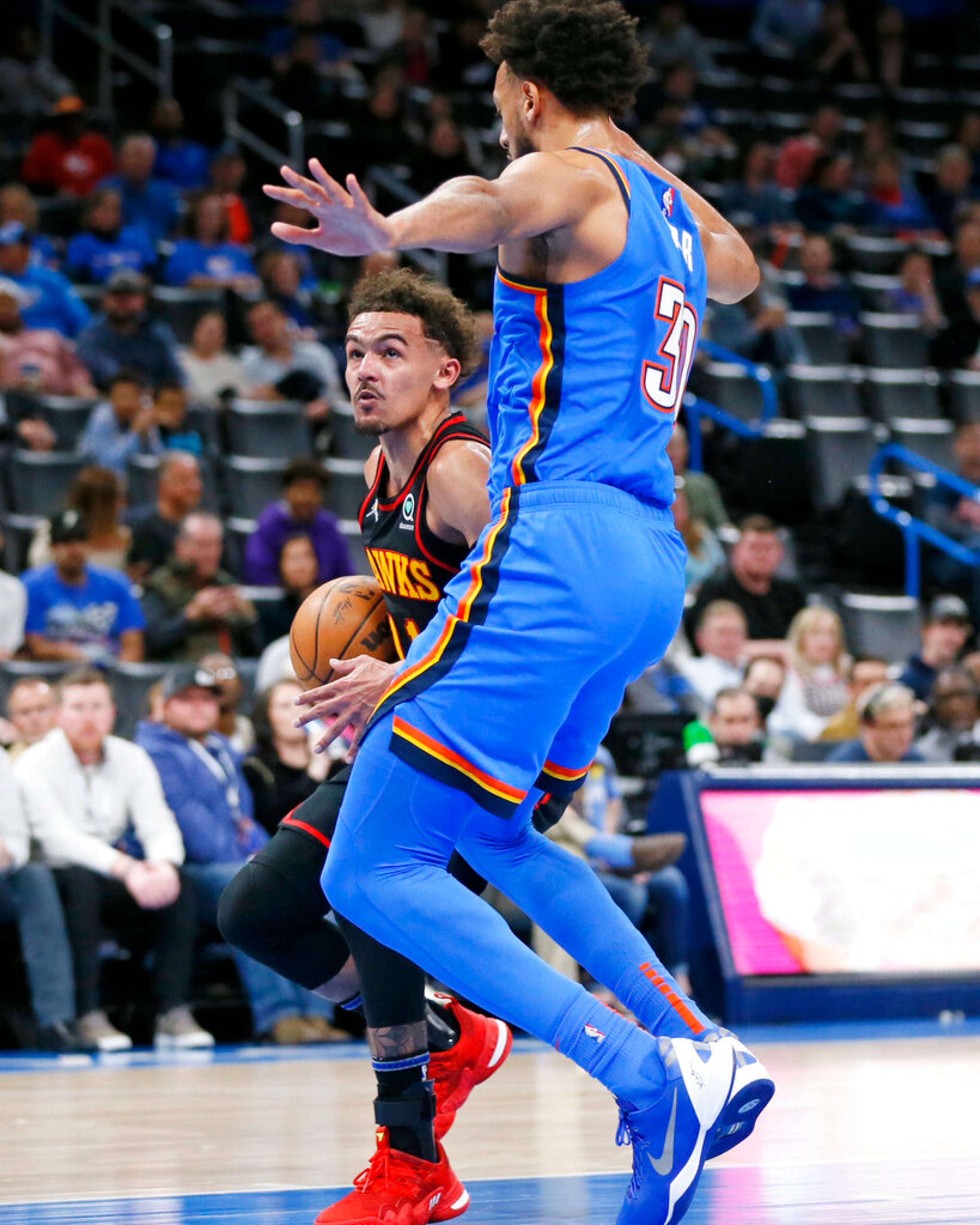 Atlanta Hawks guard Trae Young, left, is defended by Oklahoma City Thunder center Olivier Sarr during the first half of an NBA basketball game Wednesday, March 30, 2022, in Oklahoma City. (AP Photo/Nate Billings)