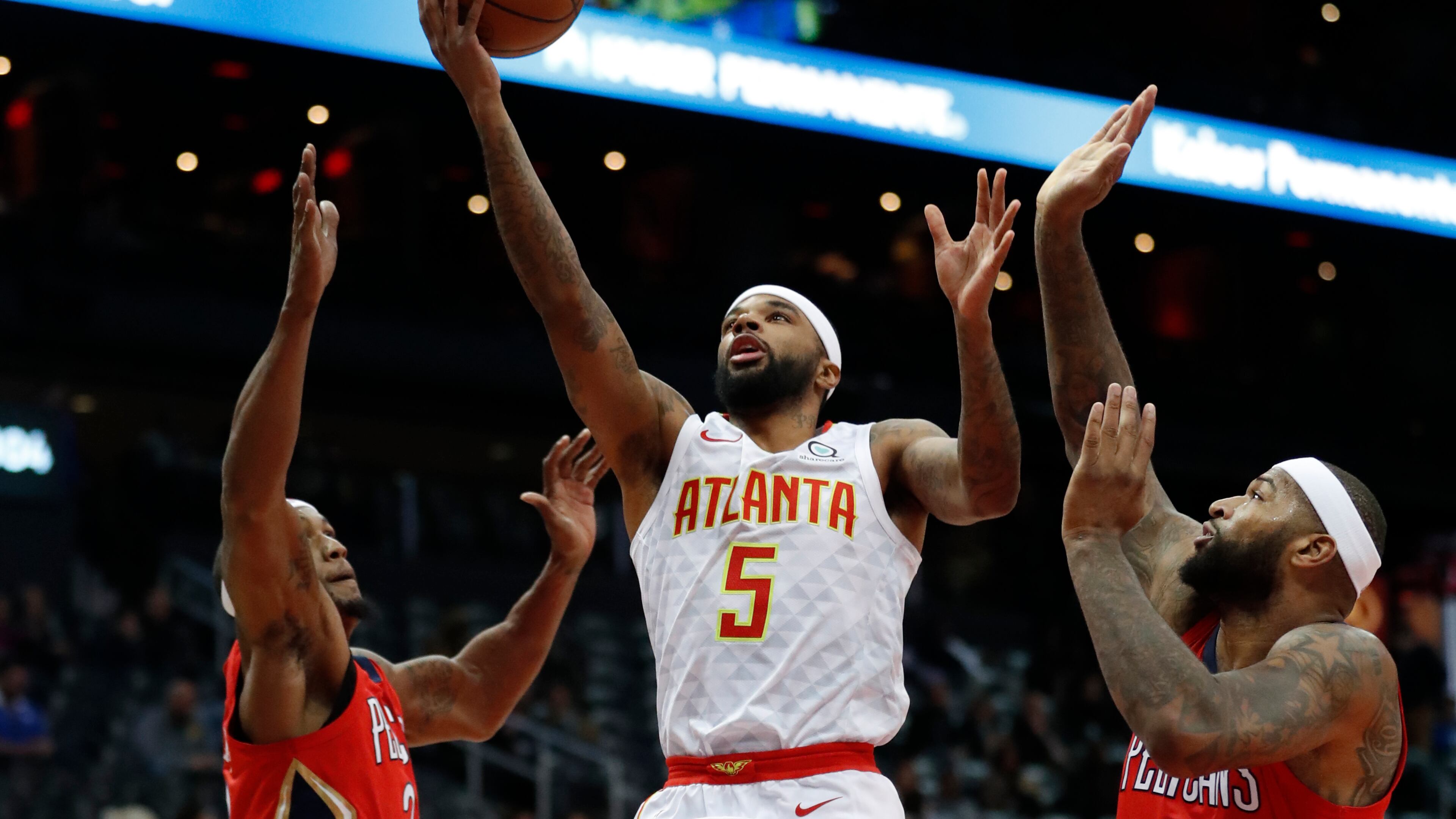Atlanta Hawks guard Malcolm Delaney (5) goes between New Orleans Pelicans' Dante Cunningham (33) and DeMarcus Cousins (0) as he goes in for a shot during the first half of an NBA basketball game Wednesday, Jan. 17, 2018, in Atlanta. (AP Photo/John Bazemore)