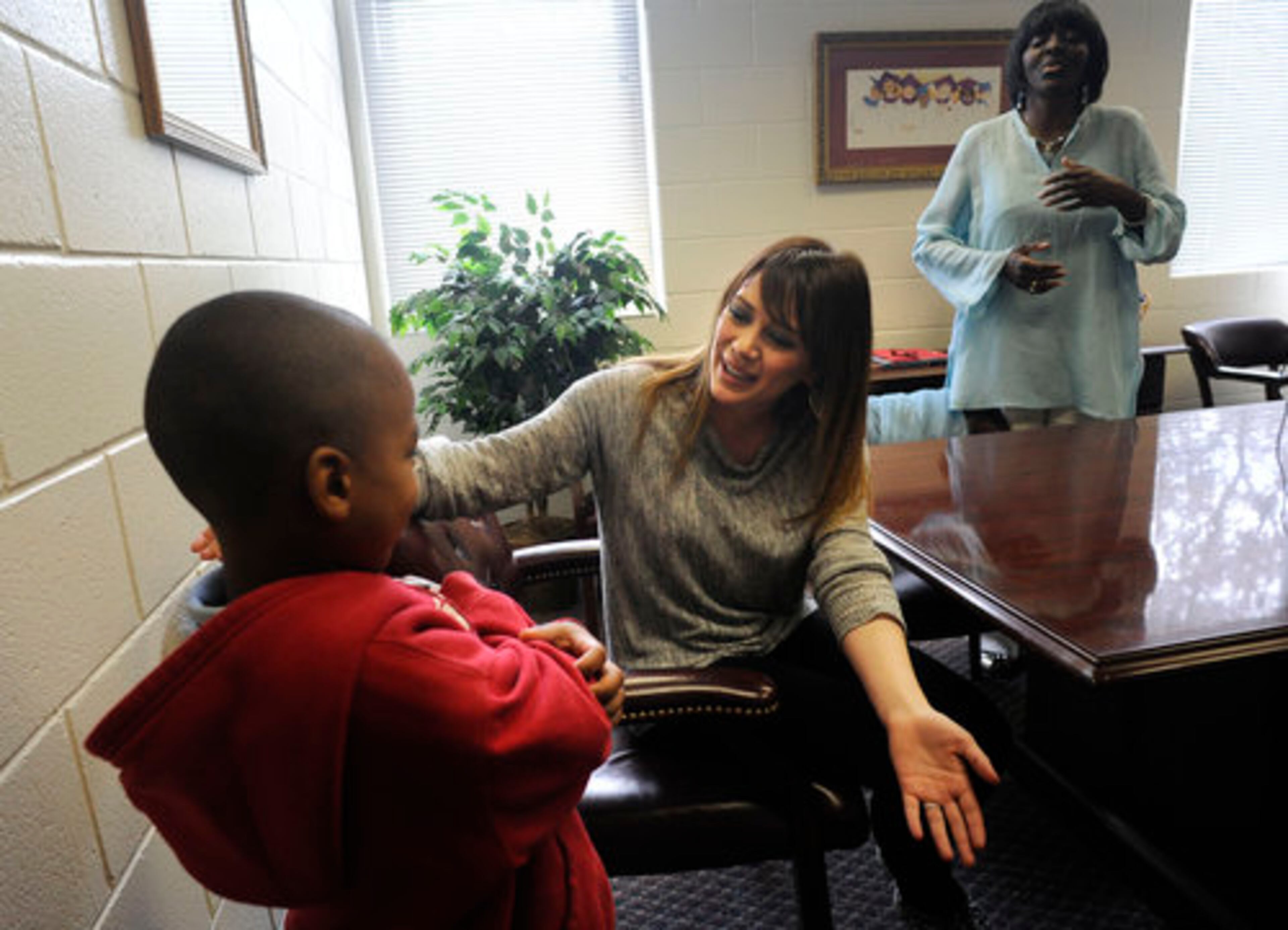 Hilary Duff offers a hug to James Ferguson, 5, as principle RoseMary Hamer looks on during her visit to Bethune Elementary School in support of the "Blessings in a Backpack" program, Monday, March 21, 2011.