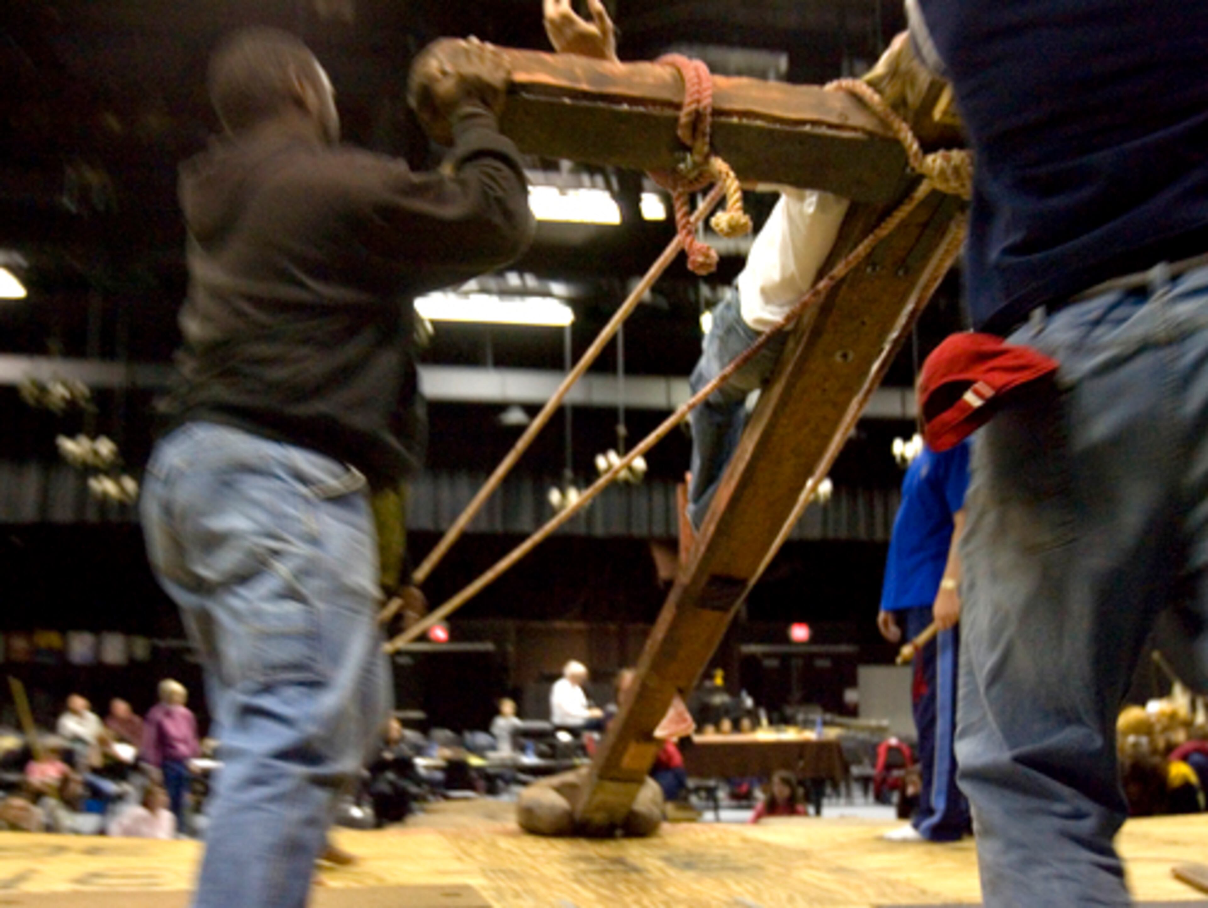 Workers hoist up the cross with Britt on it.