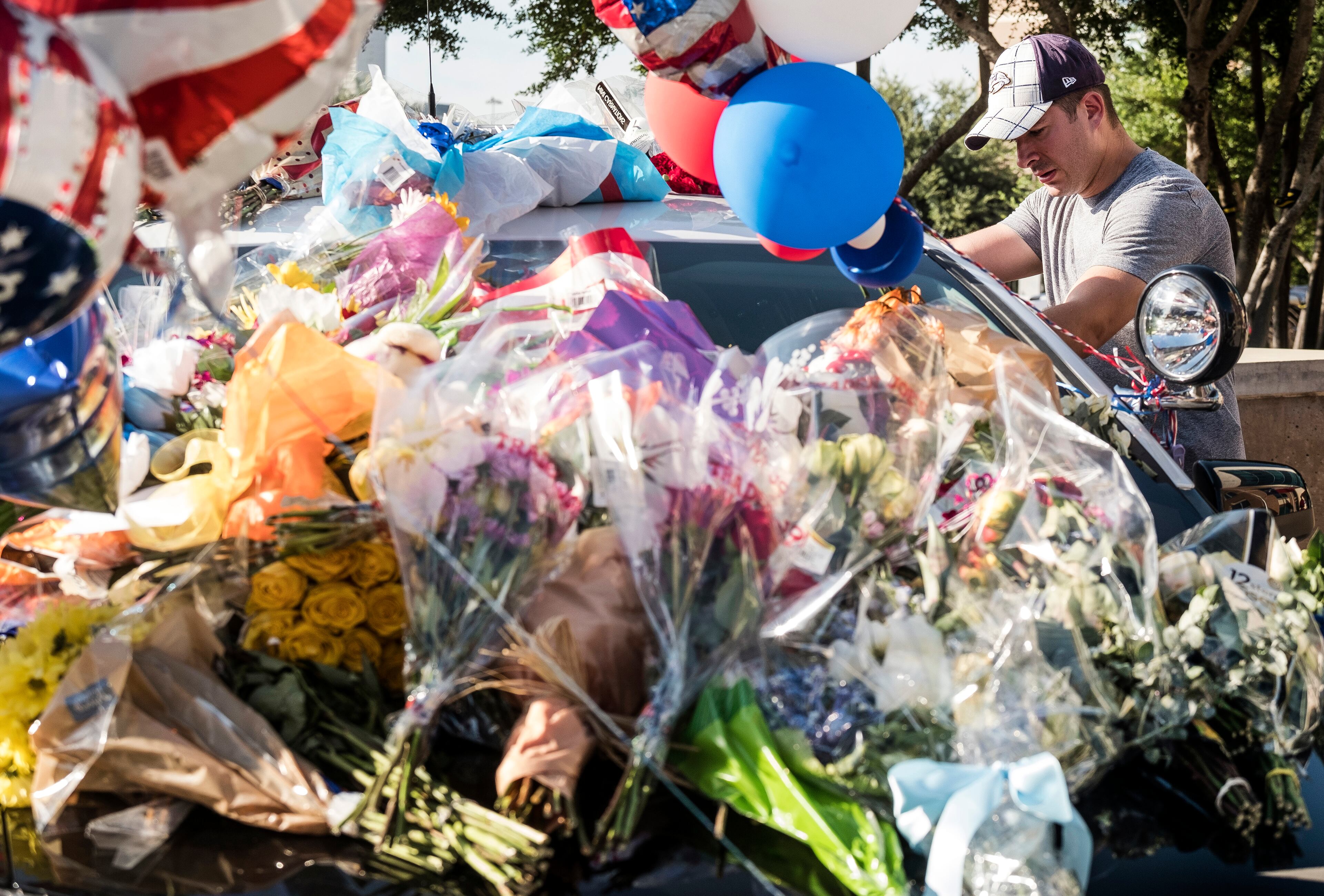 July 8, 2016 - Dallas police officer Mike Bono, off duty, pays his respect at a memorial of flowers, gifts and cards placed on Dallas patrol cars in front of the Dallas Police department headquarters in Dallas, Texas, on Friday, July 8, 2016. Five officers were killed, six officers wounded along with two civilians were shot by suspected sniper Micah Johnson. RODOLFO GONZALEZ / AUSTIN AMERICAN-STATESMAN