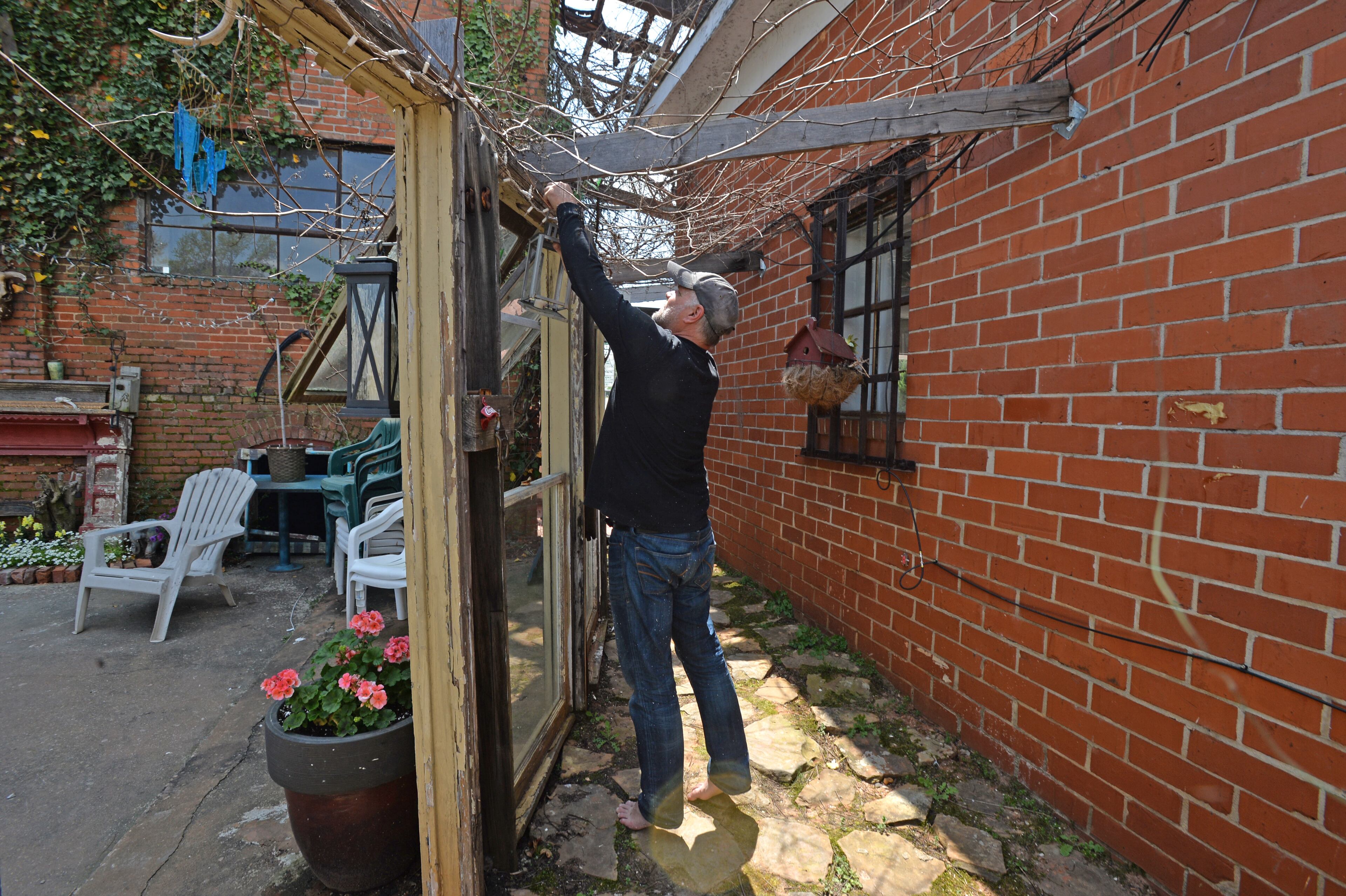 Andy Davis arranges a lamp in his backyard garden of his studio, HYOSUB SHIN / HSHIN@AJC.COM