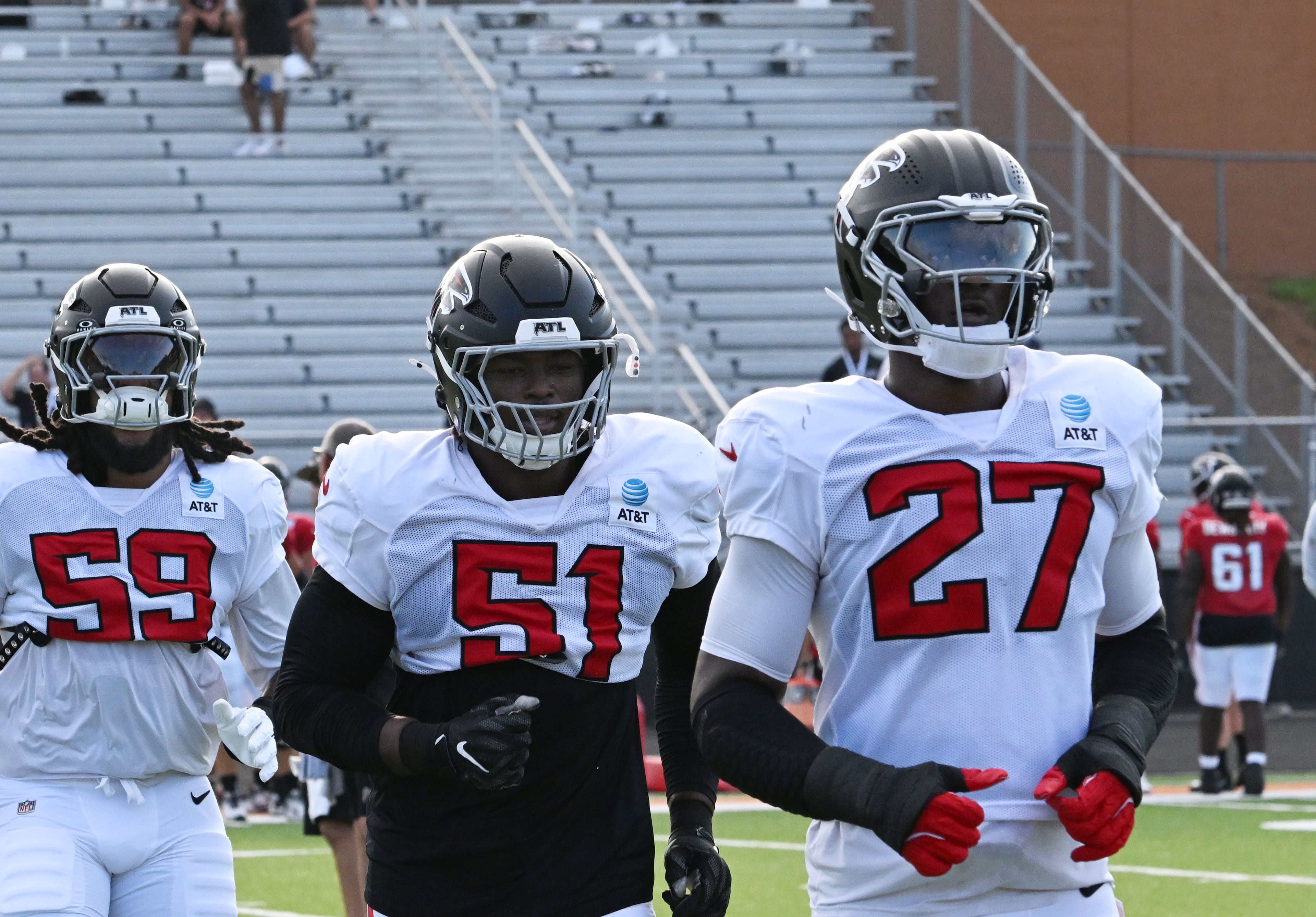 The Falcons' Keshawn Banks (left), Azeez Ojulari (center) and James Pearce Jr. (27) run a drill during the Falcons' "Saturday Night Lights" practice Saturday, Aug. 8, 2026, at Lanier High School in Sugar Hill. (Hyosub Shin/AJC)
