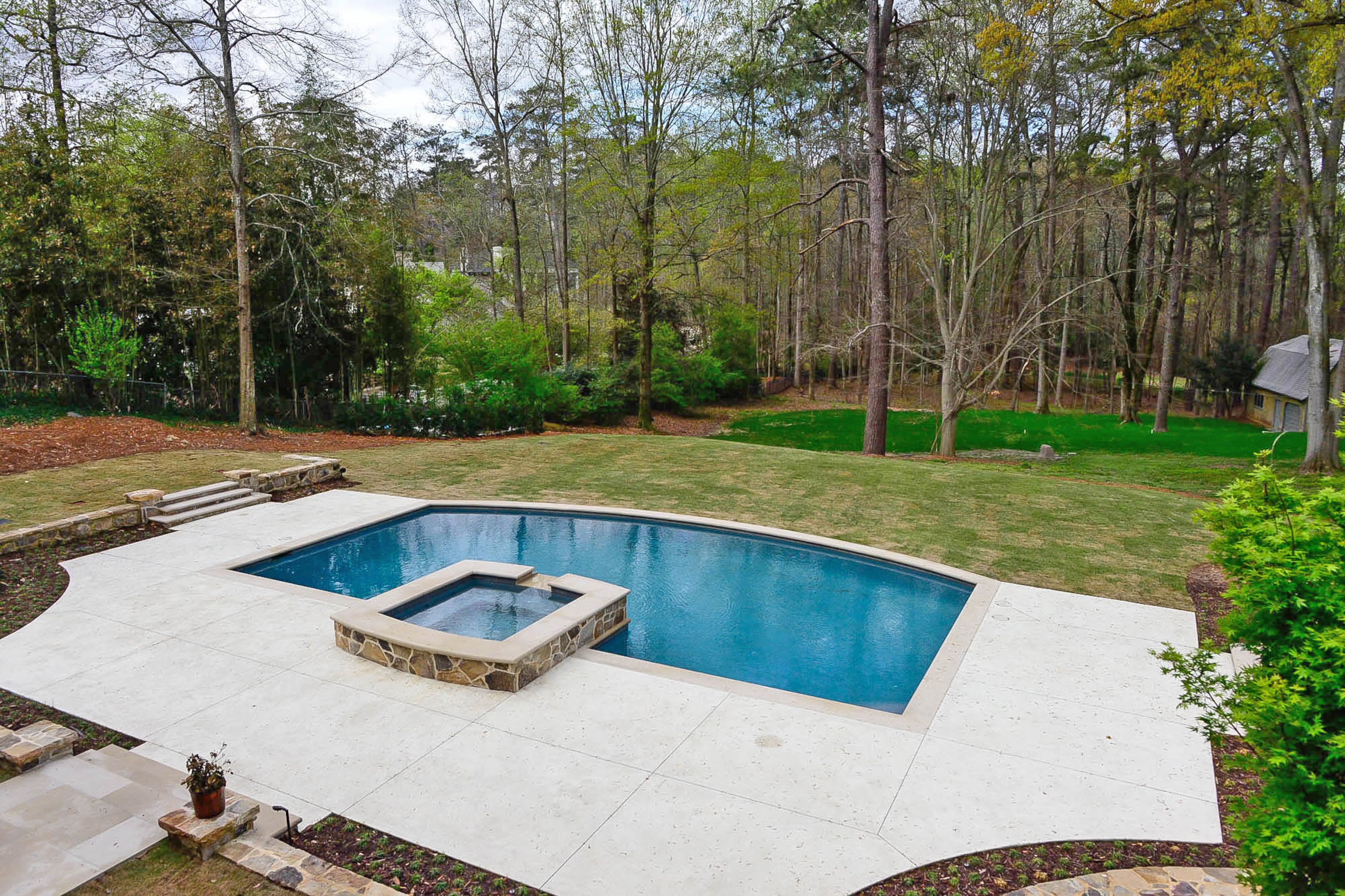 Neptune Pools gave the homeowners a pool that was big enough to swim laps and for kids to play in. The curved design of the pool, which has a hot tub and waterfall, matches the curve of the fieldstone retaining wall.
