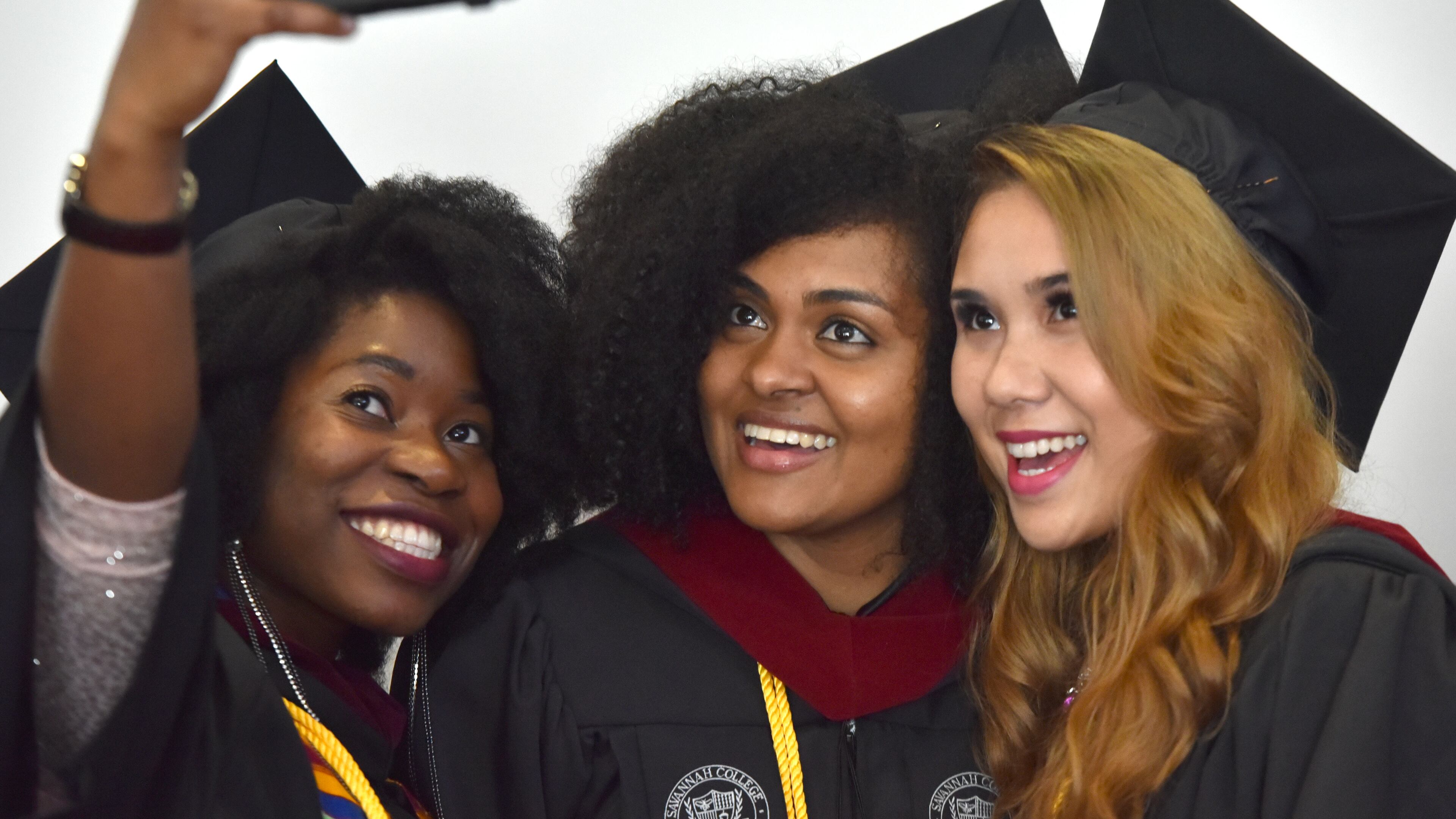 SCAD graduates (from left) Adewunmi Adetayo, Salimi Akill and Gabrielle Alvarado take selfie as they line up before SCAD commencement for the Atlanta campus at the Georgia World Congress Center on Saturday, May 30, 2015. HYOSUB SHIN / HSHIN@AJC.COM