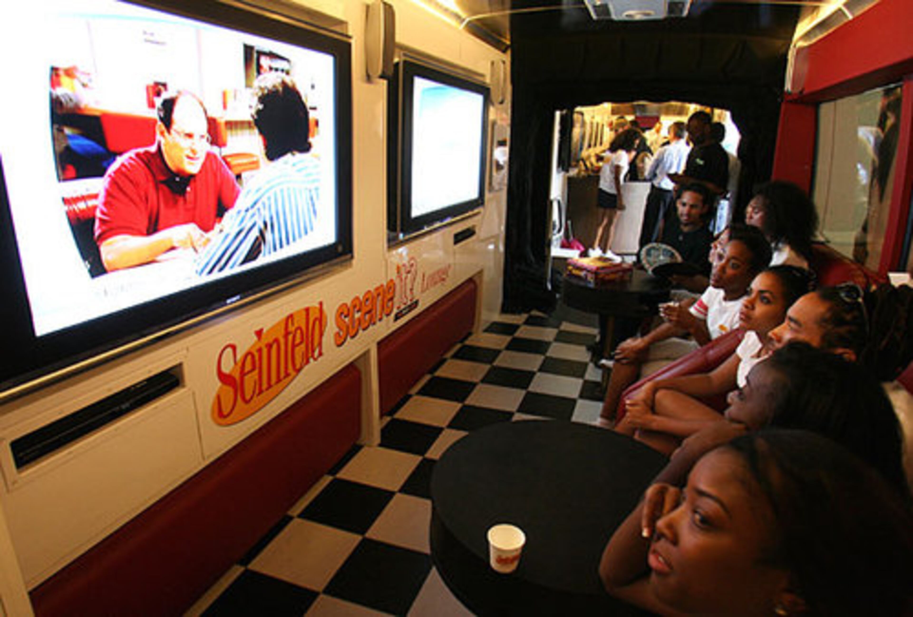 Employees sit in the cafe section of the 'Seinfeld' bus and play the Seinfeld DVD game during a stop outside Turner Field. The Seinfeld-branded bus is 60-feet long and filled with games, food and memoribilia.