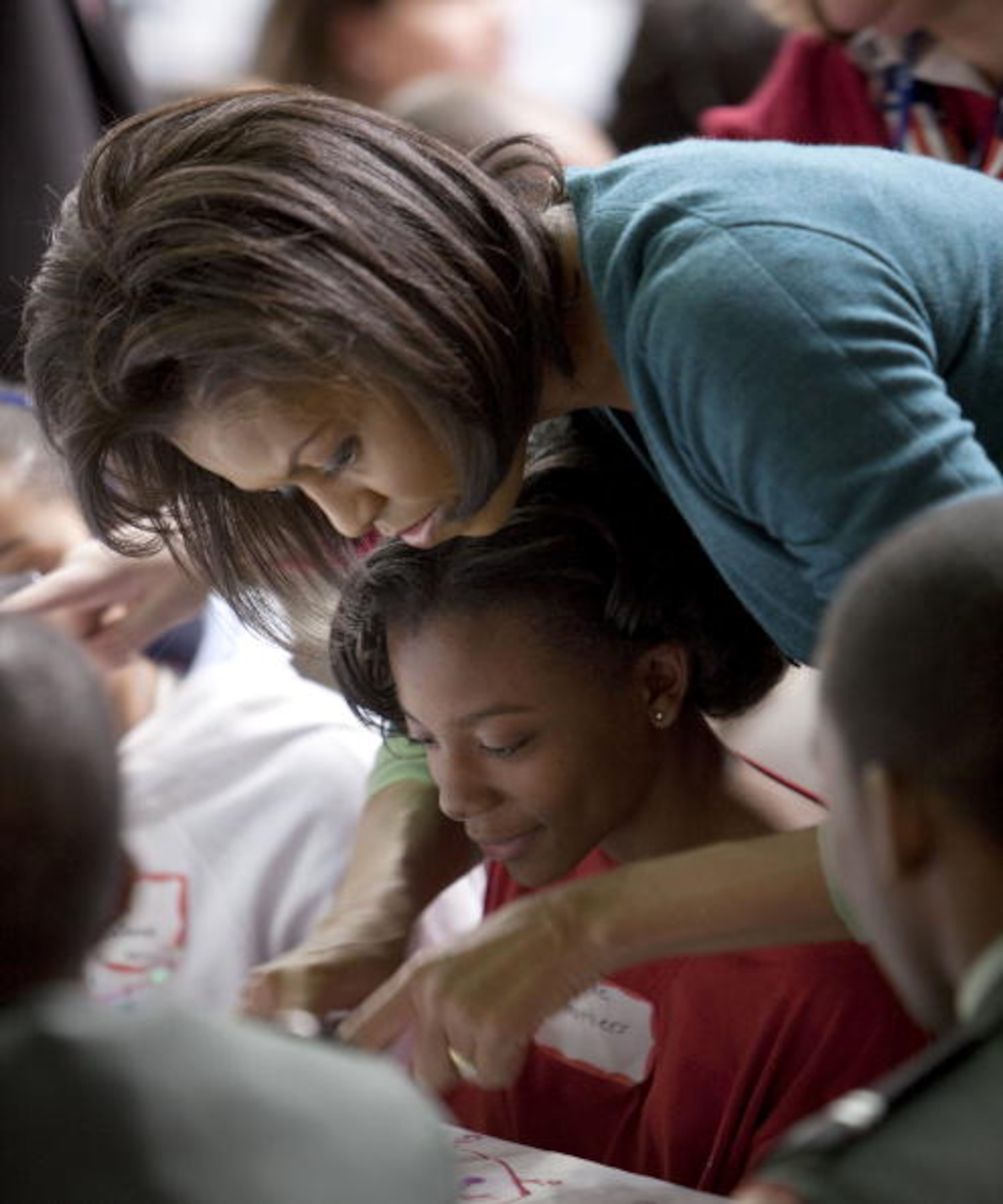 WASHINGTON - JANUARY 19: Michelle Obama helps a girl at Calvin Coolidge High School where students, military families, and volunteer service groups are working on various projects supporting the troops on January 19, 2009 in Washington, DC. Obama stopped at Calvin Coolidge High School to promote his "Day of Service" program. (Photo by Joshua Roberts-Pool/Getty Images)