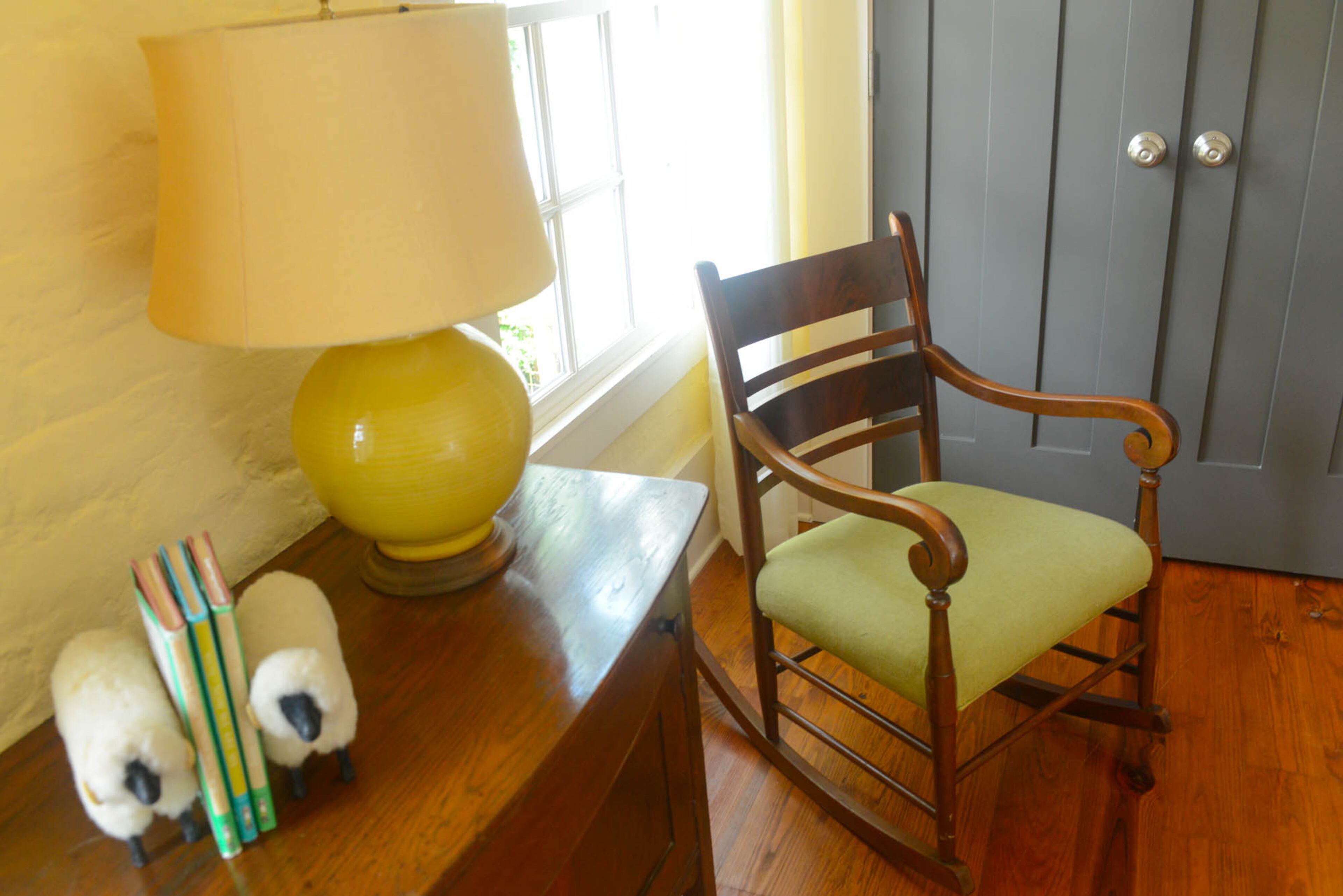 The antique rocking chair in the corner originally belonged to her mother-in-law. Simonton paired the antique chair with another family piece, her grandmother's yellow lamp, which complements the custom gray doors and pale yellow walls in her Roswell home.