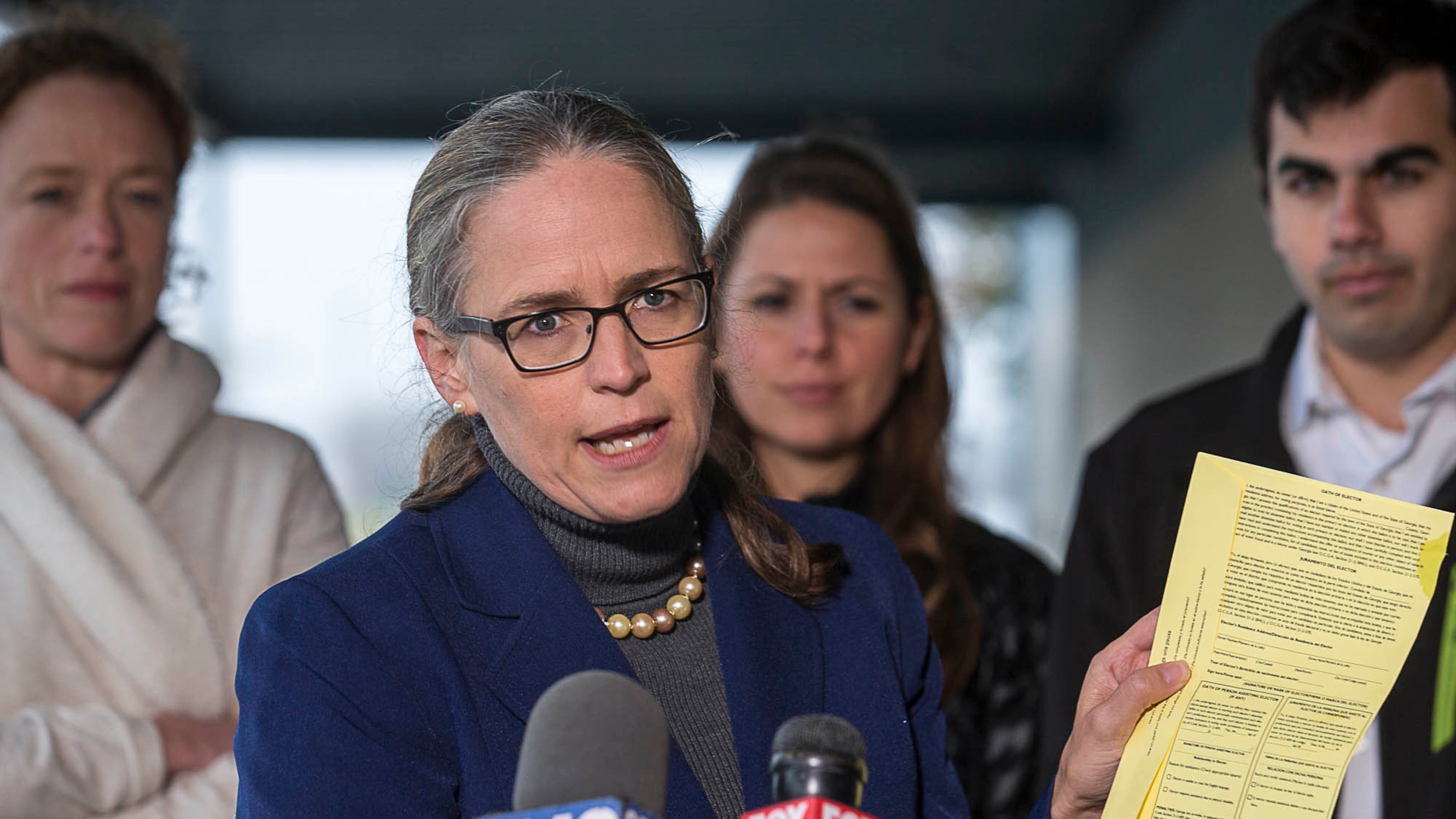 Carolyn Bourdeaux, the Democratic nominee for Georgia’s 7th Congressional District, displays a Gwinnett County absentee ballot as she speaks during a press conference Monday outside the Gwinnett County Board of Voter Registration and Elections in Lawrenceville. Bourdeaux’s campaign filed an emergency motion Sunday night seeking to force Gwinnett County to count previously rejected absentee ballots for the 2018 midterm elections. (ALYSSA POINTER/ALYSSA.POINTER@AJC.COM)