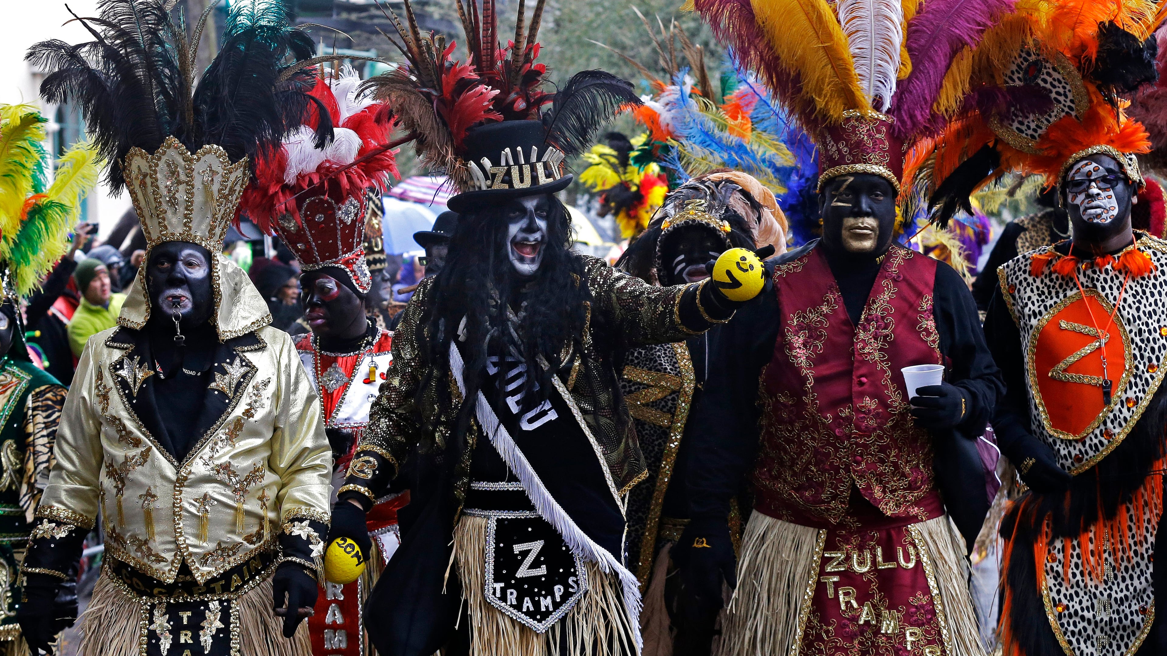 Members of the Krewe of Zulu hold painted coconuts to give to paradegoers as they march during Mardi Gras in New Orleans.