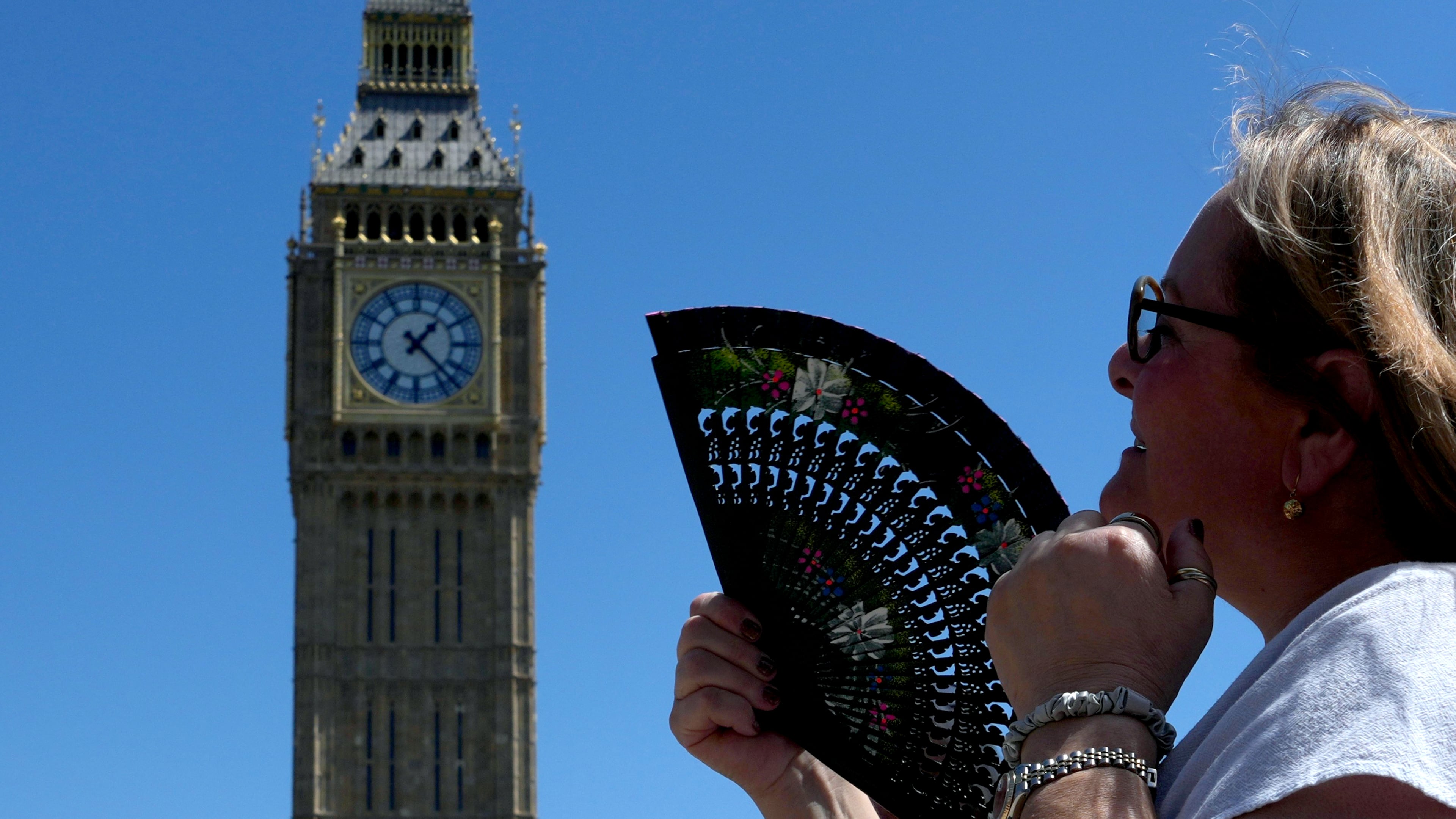 FILE - A woman cools herself outside the Palace of Westminster in London, May 26, 2026. (AP Photo/Kin Cheung, File)