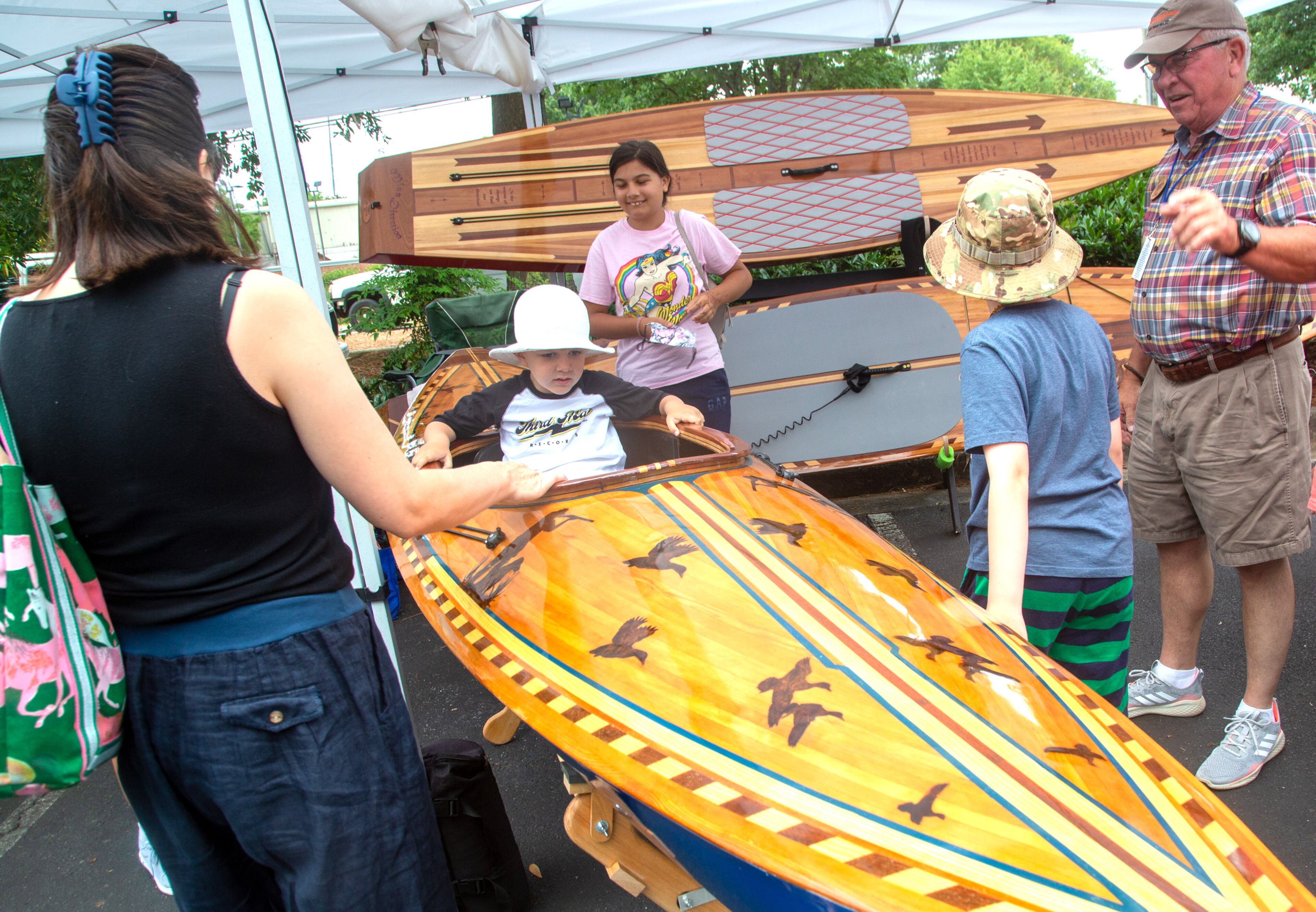 Shane Olson (center) sits in a handcrafted kayak during the Roswell Spring Arts and Crafts Festival on Sunday, June 13, 2021. (Photo: Steve Schaefer for The Atlanta Journal-Constitution)