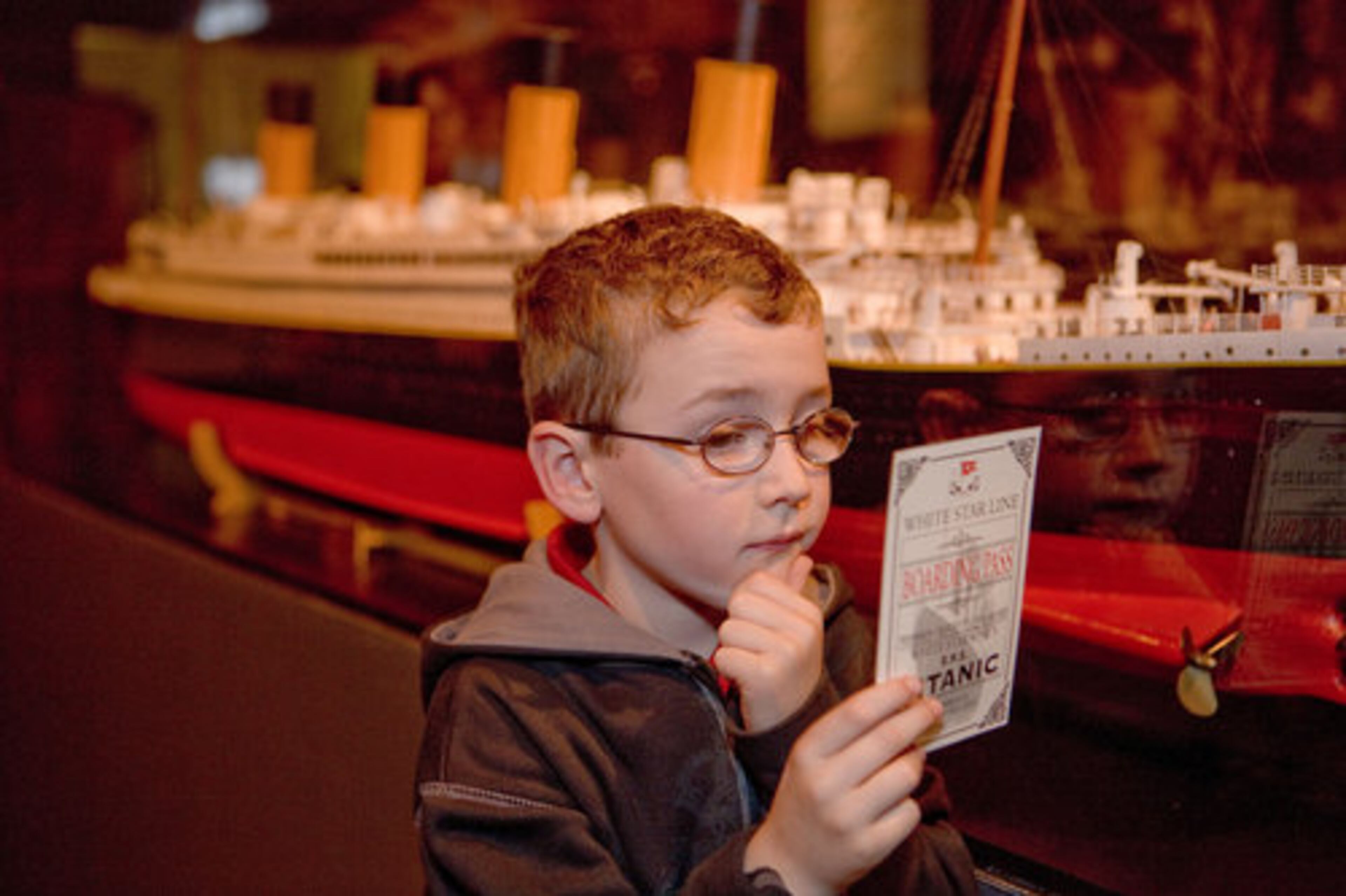 A young exhibition visitor holds a replica Titanic boarding pass.