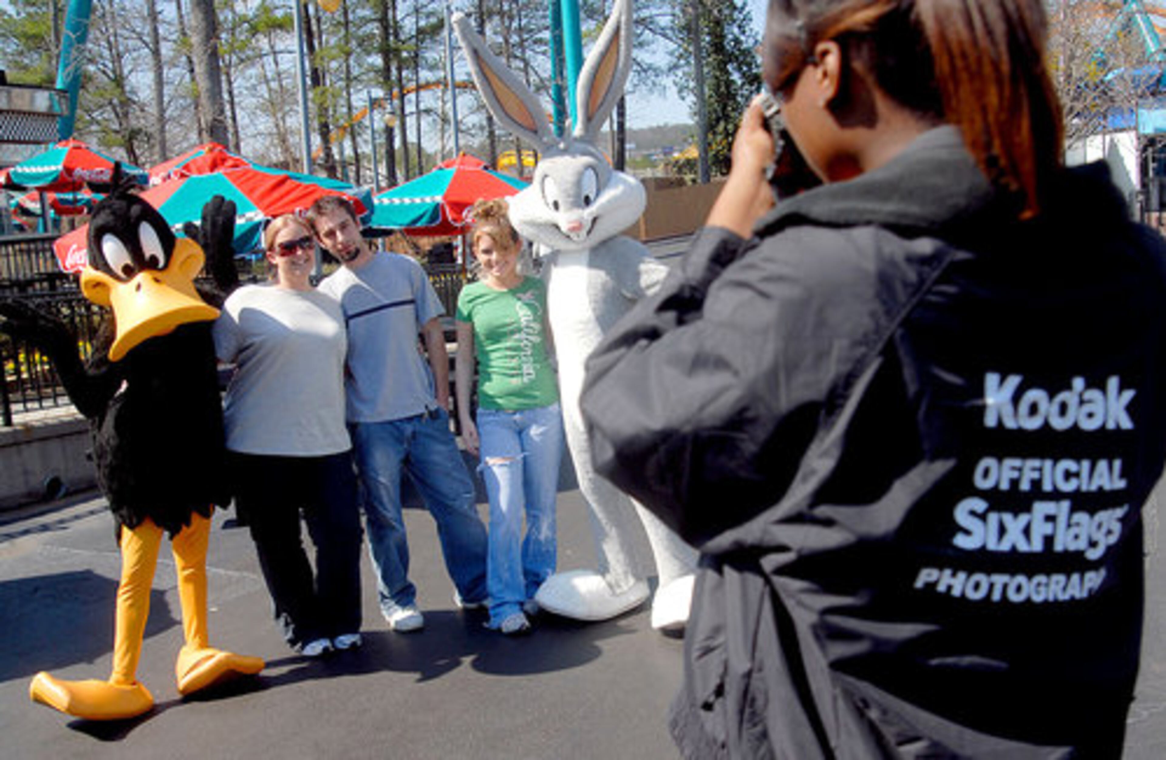 Ashley (from left) and Louis Prioreschi, with Kelsey Woodard, smile as park photographer Moyia Thomas snaps a shot of them with Daffy and Bugs.