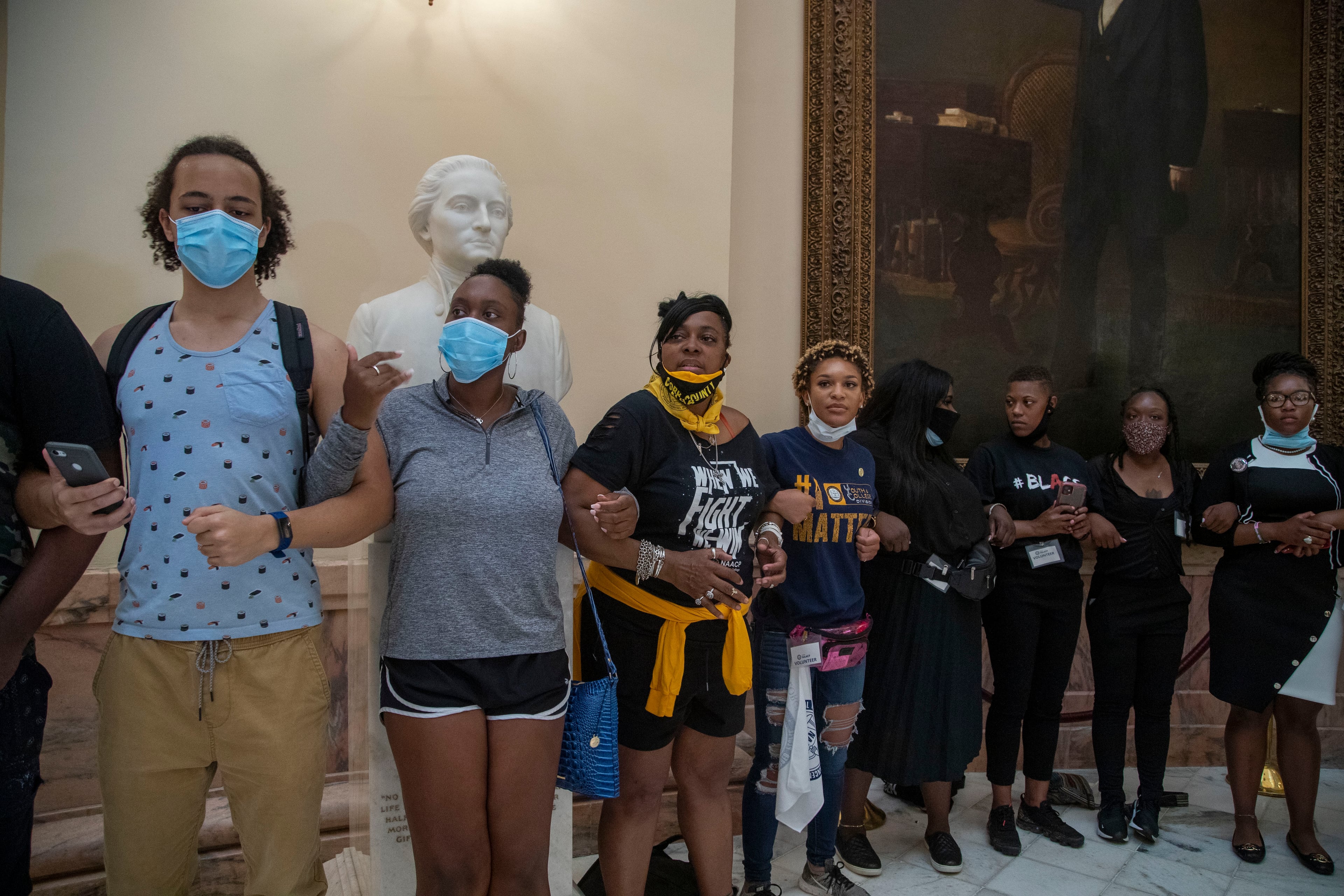 06/15/2020 - Atlanta , Georgia - People link arms as they protests in the rotunda at the Georgia State Capitol building, Monday, June 15, 2020. This is the 30th day of the legislative session and the first day back for legislators following a break due to COVID-19. (ALYSSA POINTER / ALYSSA.POINTER@AJC.COM)