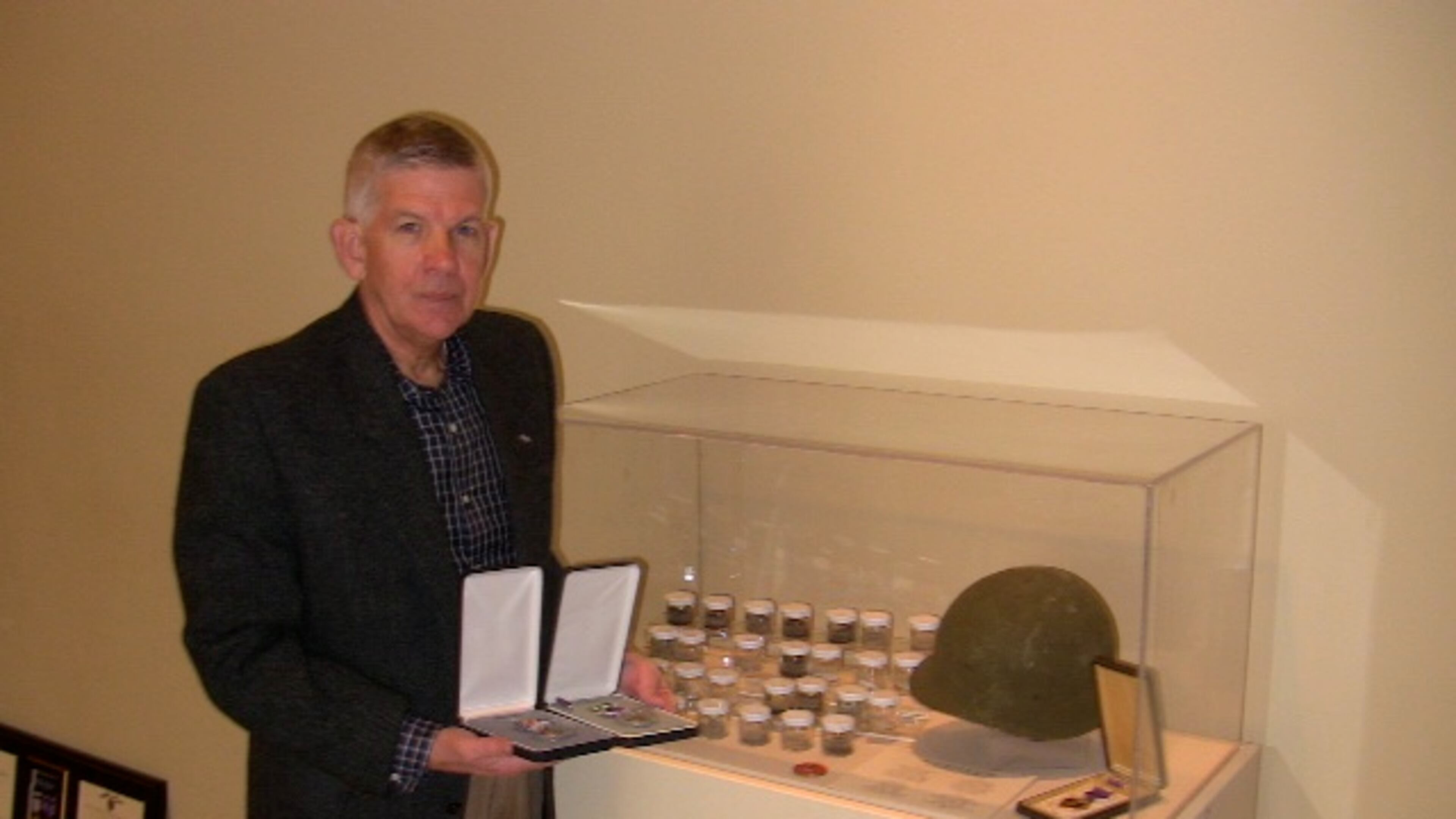 Insurance executive Bob Moore, who received his Silver Star four decades late, looking at an exhibit at the Atlanta History Center of dirt from Vietnam and other foreign battlefields.