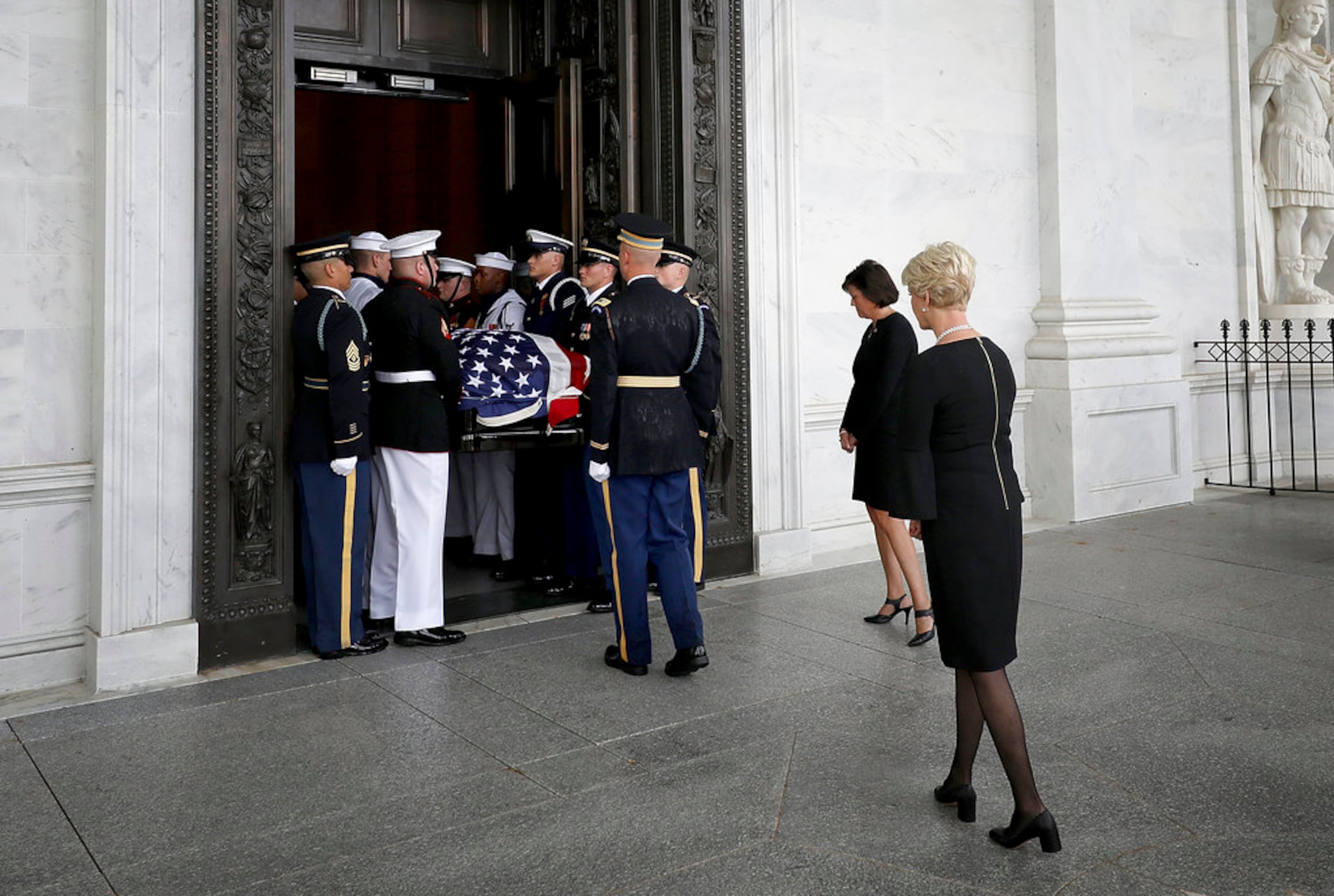 The flag-draped casket of Sen. John McCain, R-Ariz., is carried up the steps of the U.S. Capitol, Friday, Aug. 31, 2018, in Washington as Cindy McCain looks on. (Win McNamee/Pool photo via AP)