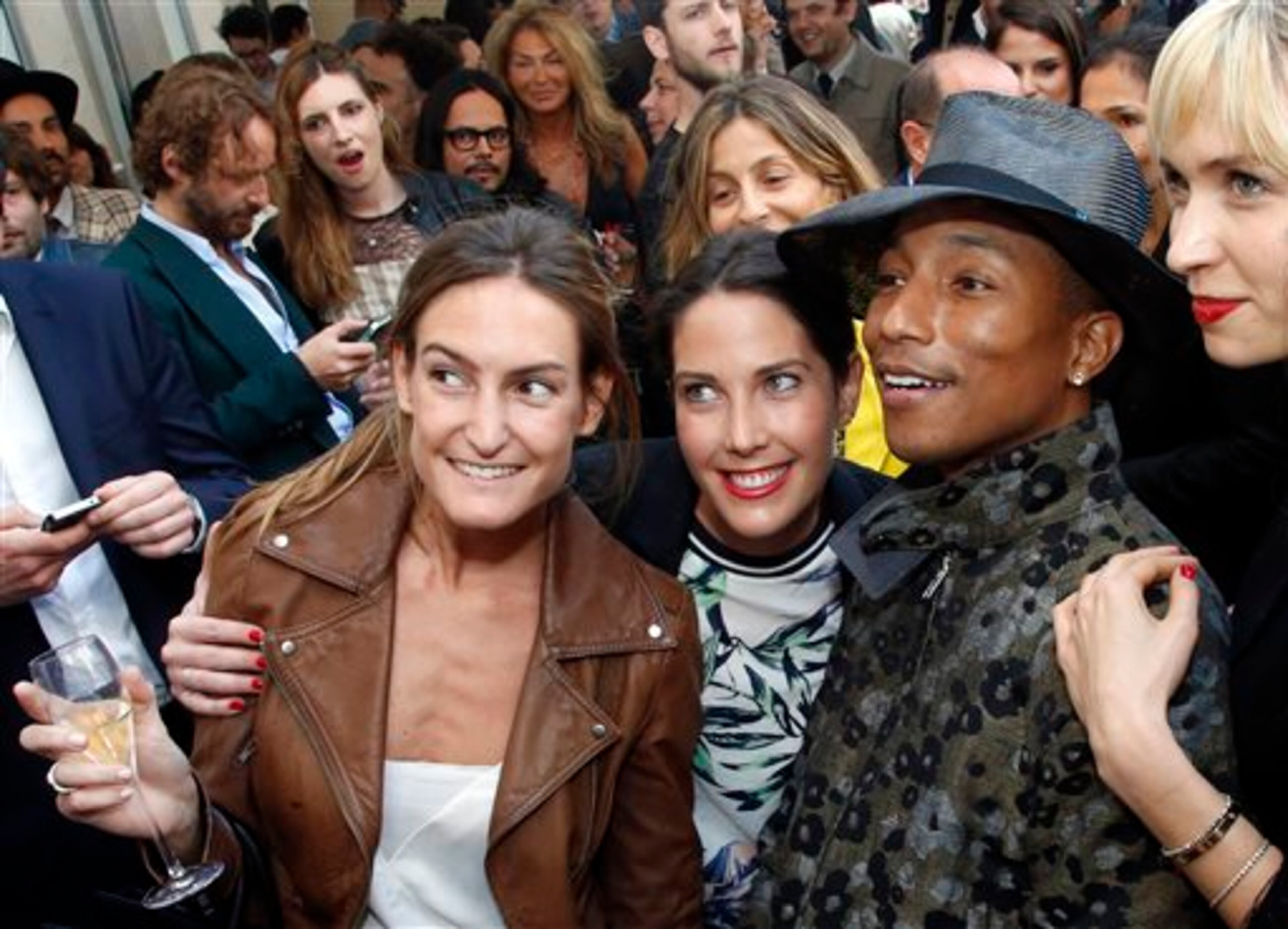 Singer Pharrell Williams, second from right, poses with fans prior to his performance on stage during a private concert for the exhibition "GIRL" at the Perrotin Gallery in Paris, Monday, May 26, 2014. Williams curated an exhibition encompassing around 40 art pieces, presenting their visions of femininity, muses, female creativity and freedom. The show opens on May 27 and runs through June 27. (AP Photo/Francois Mori)