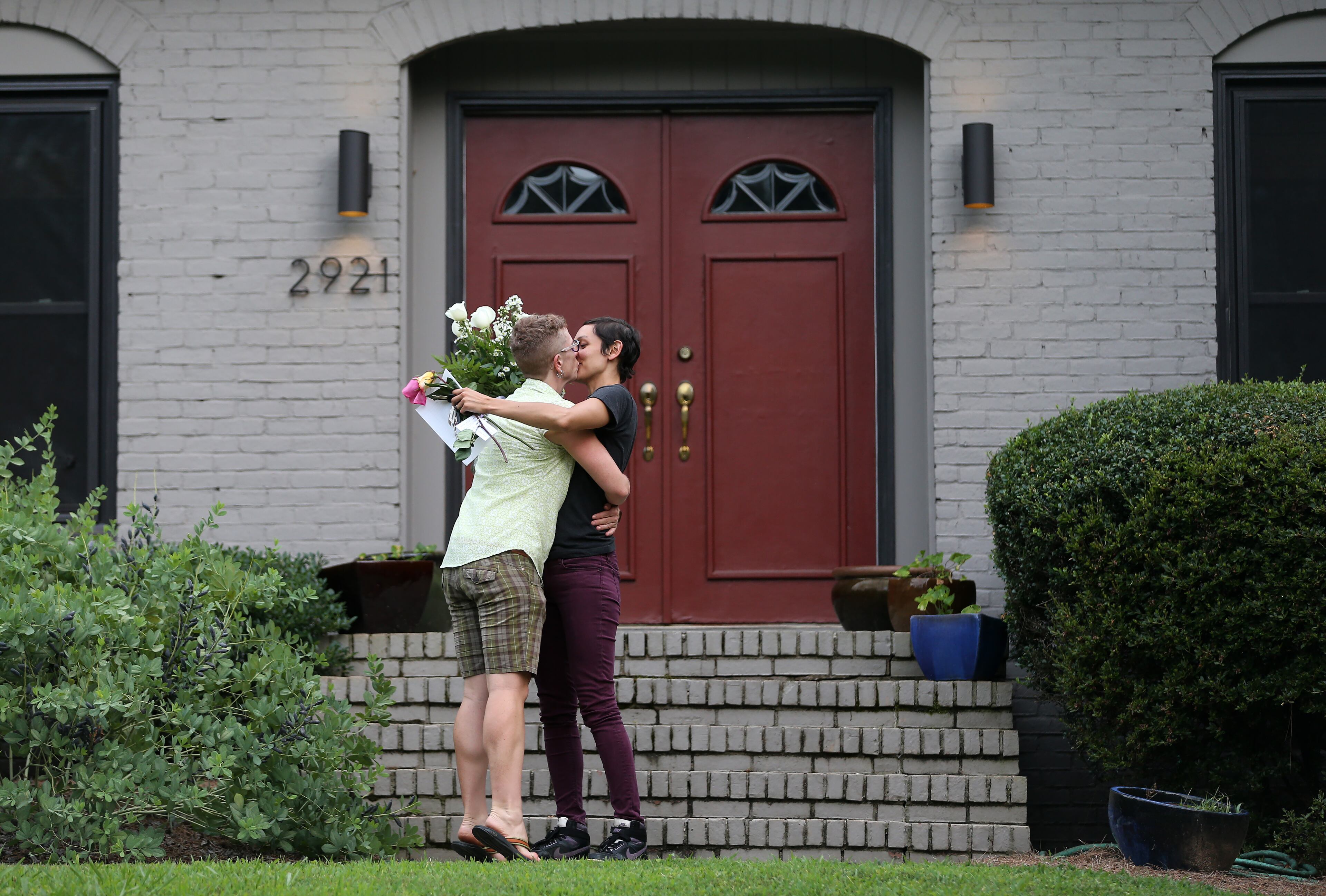 June 26, 2015 Decatur: Cath, left, and Laura Rivera-Simonsen kiss after arriving at their Decatur home to find a delivery of a dozen white roses from one of Cath's coworkers left on their doorstep Friday June 26, 2015. The couple, who have been together for more than a year, weren't planning for Friday to be their wedding day, but that changed after the Supreme Court decision legalized same-sex marriage in Georgia and across the country. The couple tied the knot during a ceremony in the Fulton County Commission chambers and then again with a minister on the steps of the Fulton County Courthouse. Ben Gray / bgray@ajc.com