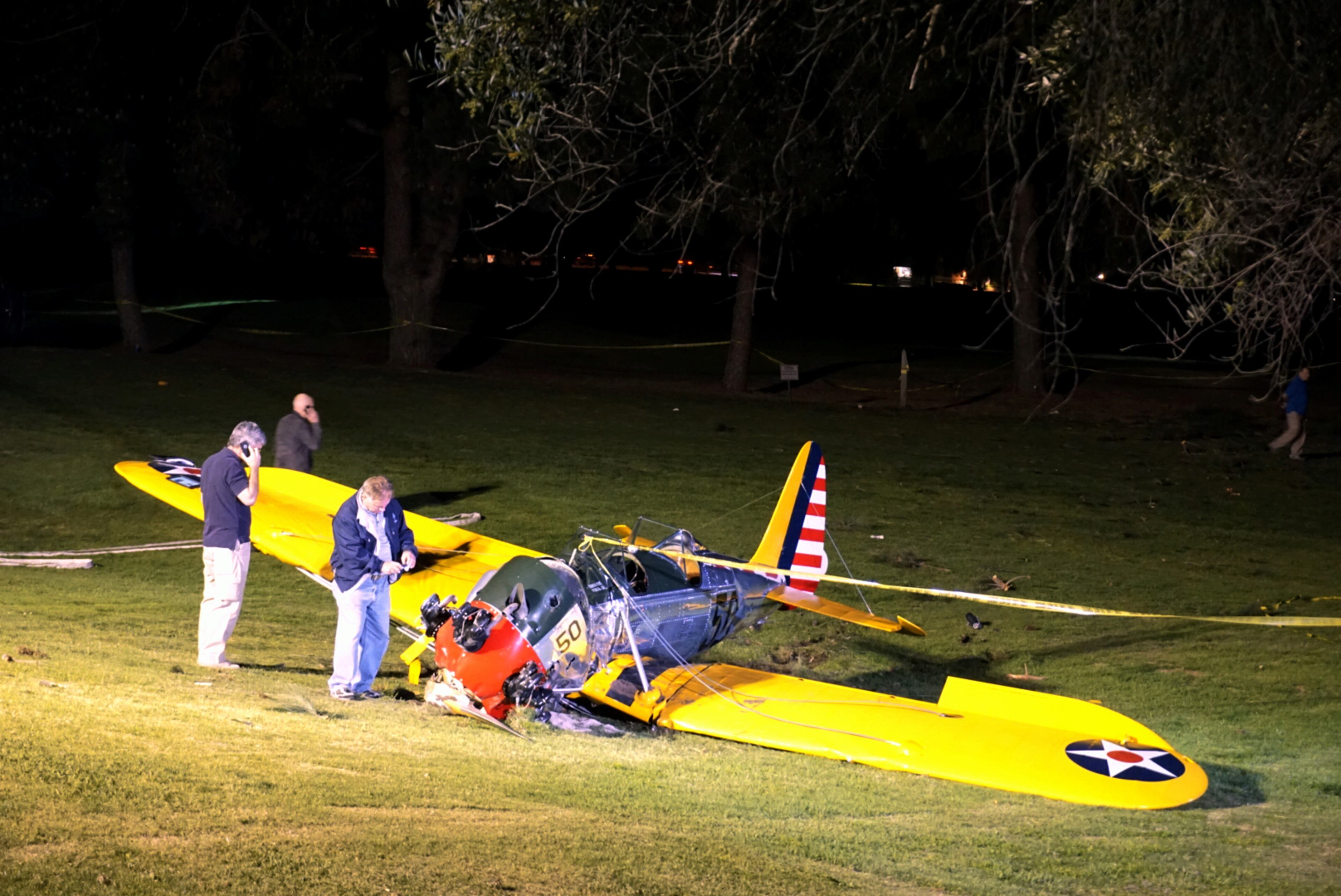 Officials work on the scene of a vintage airplane that crash-landed on the Penmar Golf Course in the Venice area of Los Angeles, Thursday, March 5, 2015. Harrison Ford crash-landed the airplane shortly after taking off from a nearby airport and reporting engine problems. (AP Photo/Damian Dovarganes)