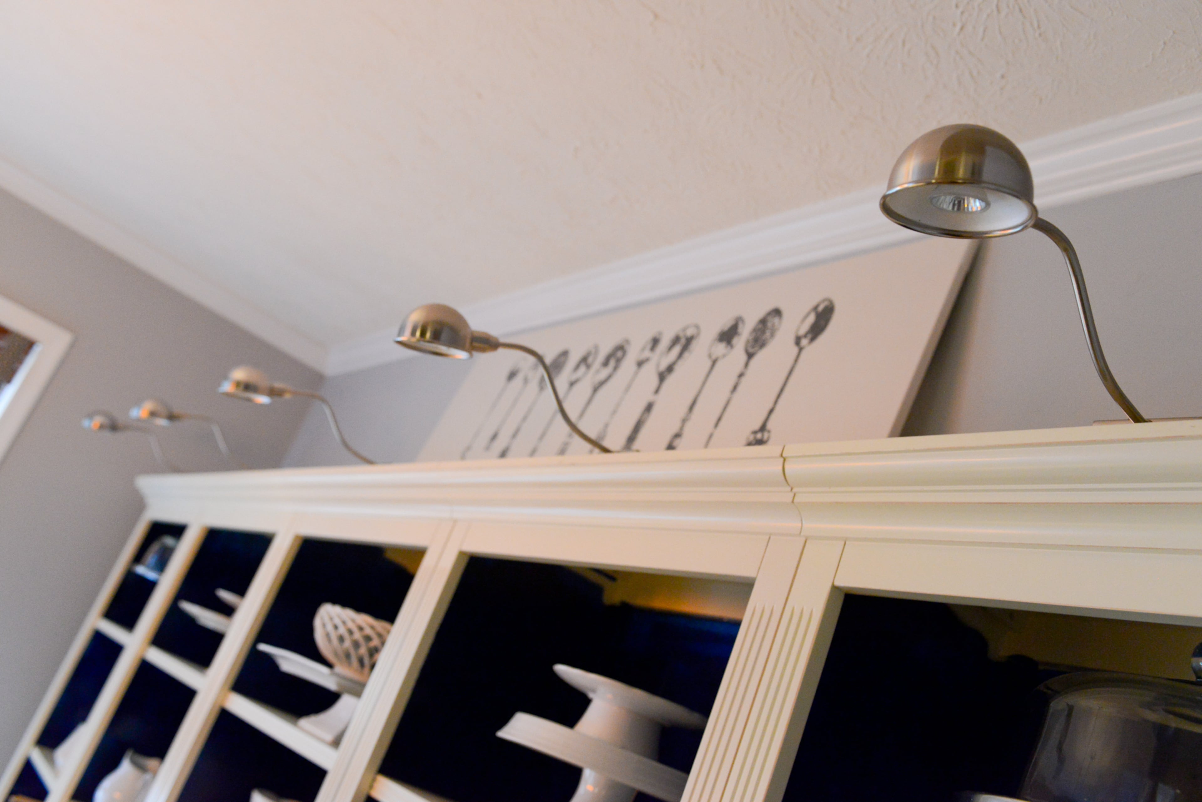 Spotlights from Ikea along the top of a Ballard Designs bookcase provide ambient light for hosting dinner parties.