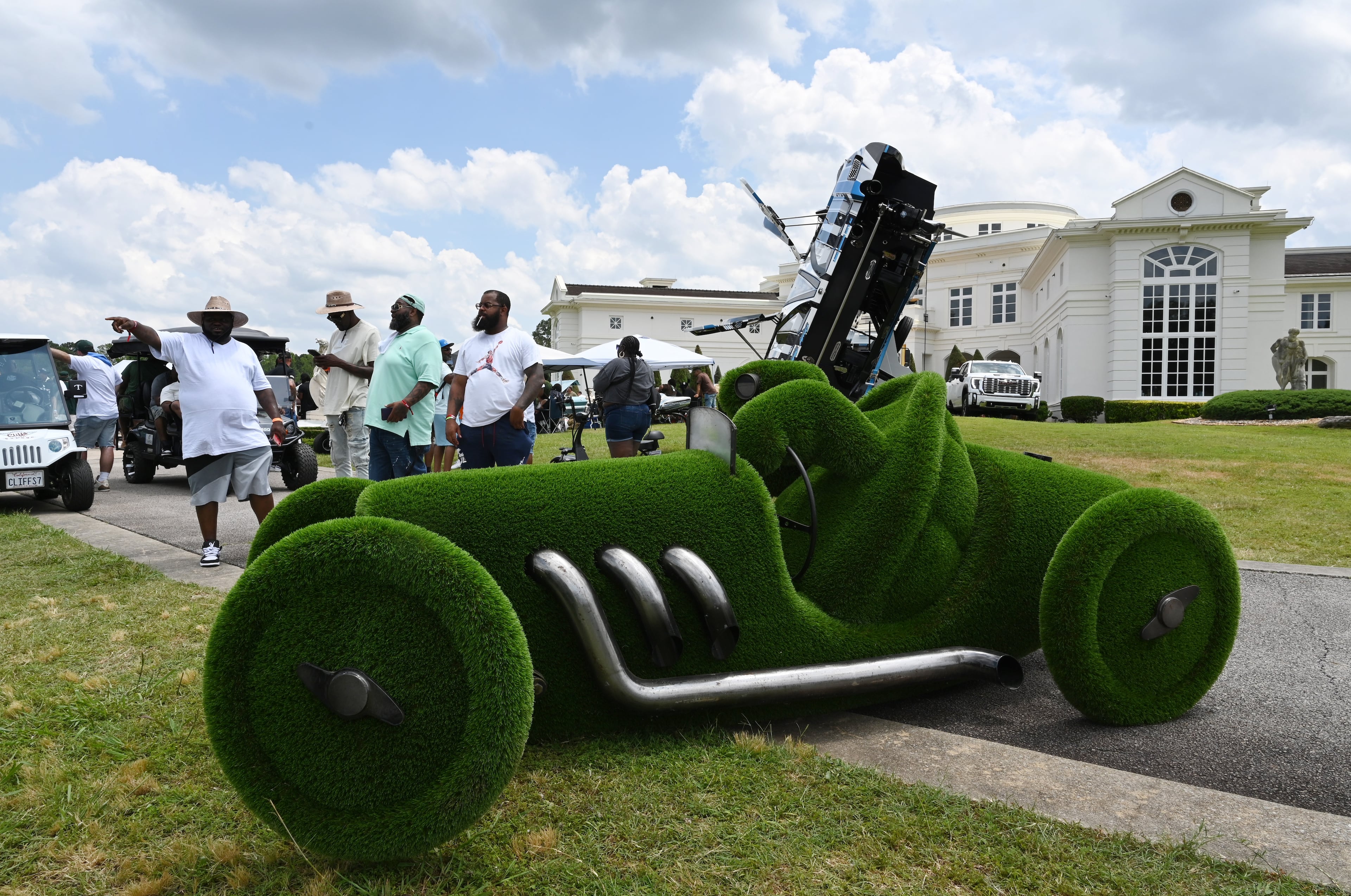 Attendees walk through fleets of classic/custom automobiles, luxury vehicles, boats, RVs and trailers on the front of the mansion during the 4th Annual Rick Ross Car and Bike Show, Saturday, June 7, 2025, in Fayetteville. The 4th Annual Rick Ross Car and Bike Show will include a vendor market with more than 30 vendors, food trucks, fleets of classic/custom automobiles, luxury vehicles, boats, RVs and trailers on the front of the mansion. Stage performances include Plies, Ross' new signee Nino Breeze and Ross himself. (Hyosub Shin / AJC)