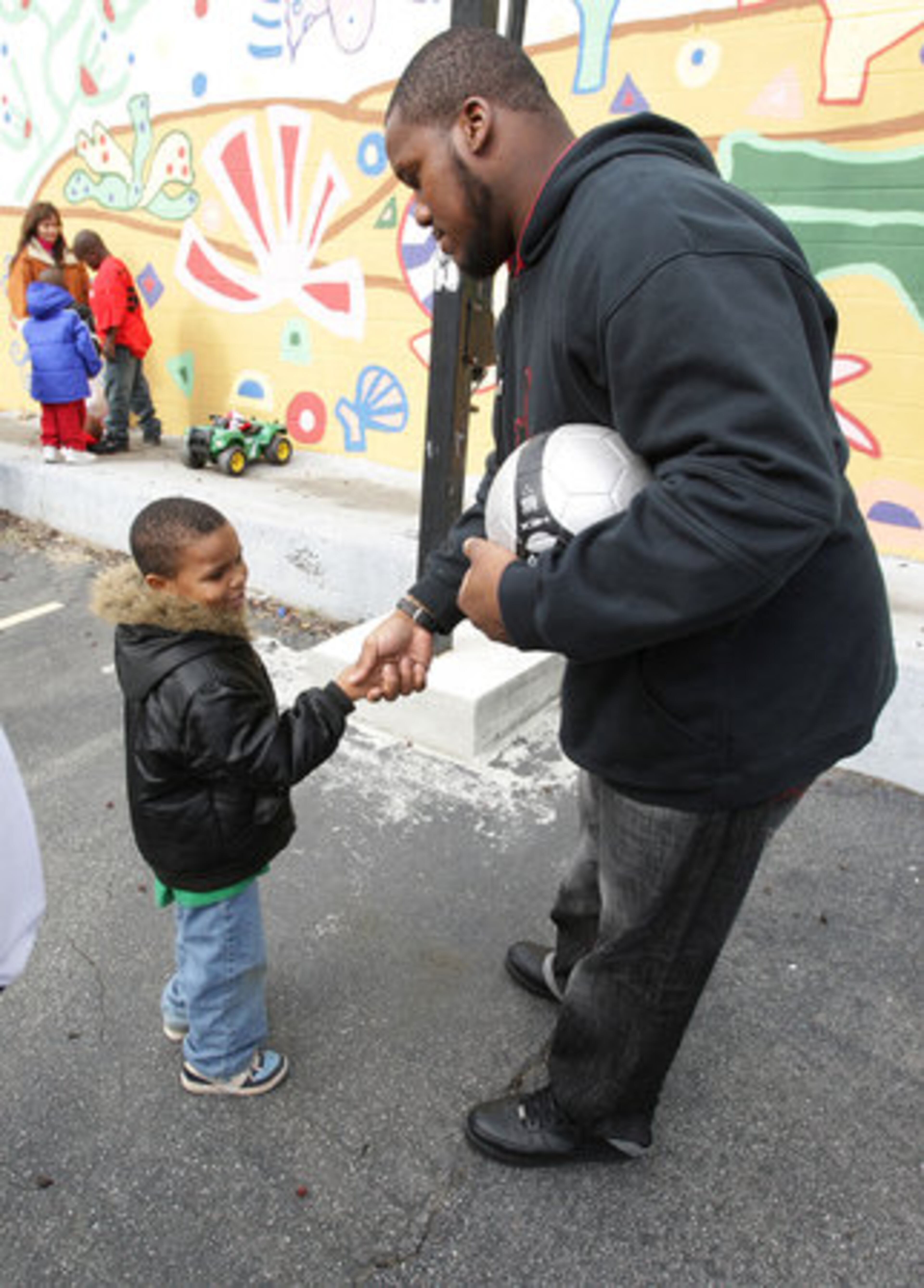 Daquon Henderson shakes hands with Falcon Jonathan Babineaux after the pair played a game of basketball.