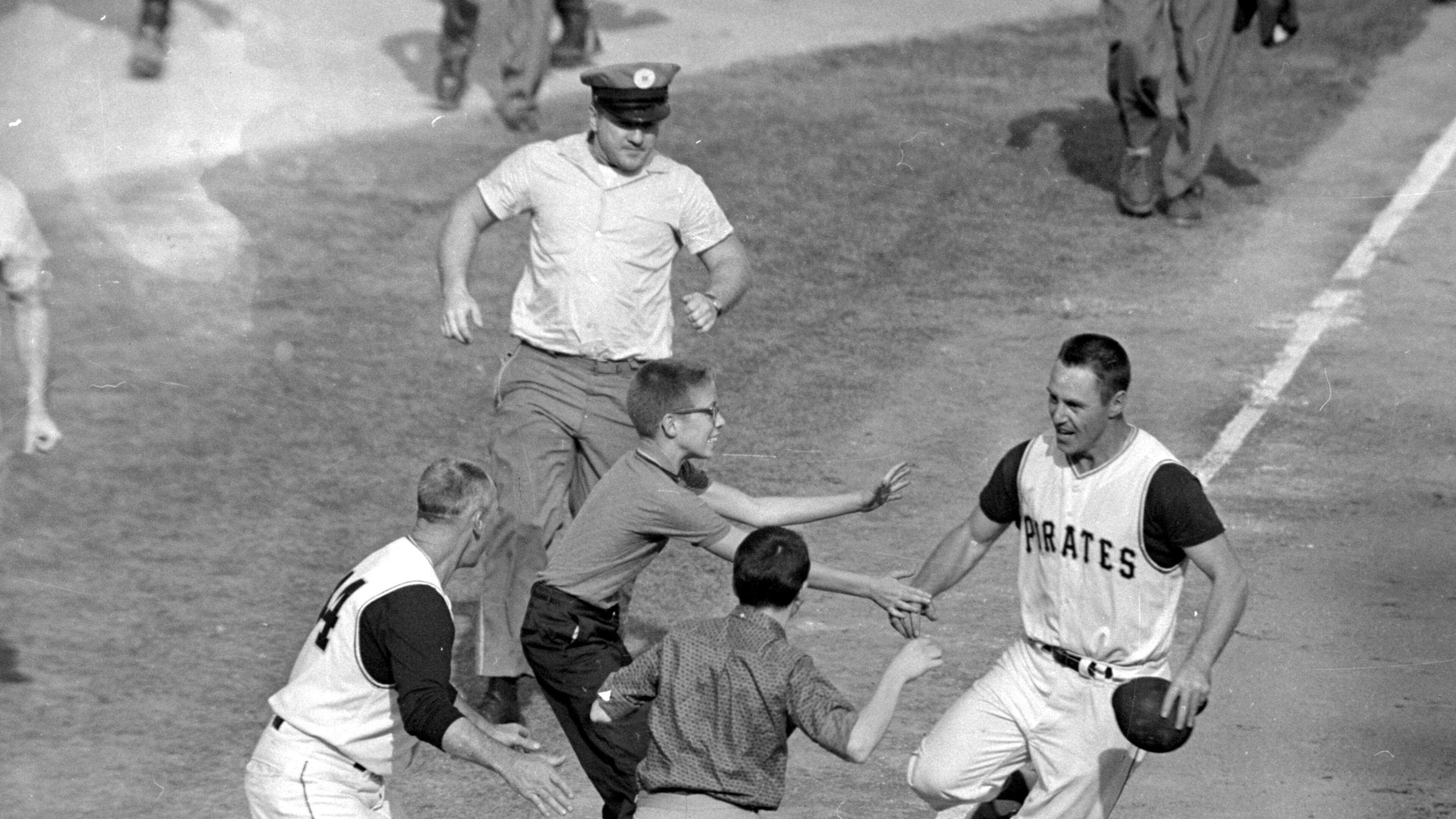 FILE - In this Oct. 13, 1960 file photo, jubilant Pittsburgh Pirates fans rush onto the field to congratulate second baseman Bill Mazeroski as he rounds third base after hitting a ninth inning home run to win Game 7 of baseball's World Series against the New York Yankees in Pittsburgh, Pa., on Oct. 13, 1960. (AP Photo/Harry Harris, File)