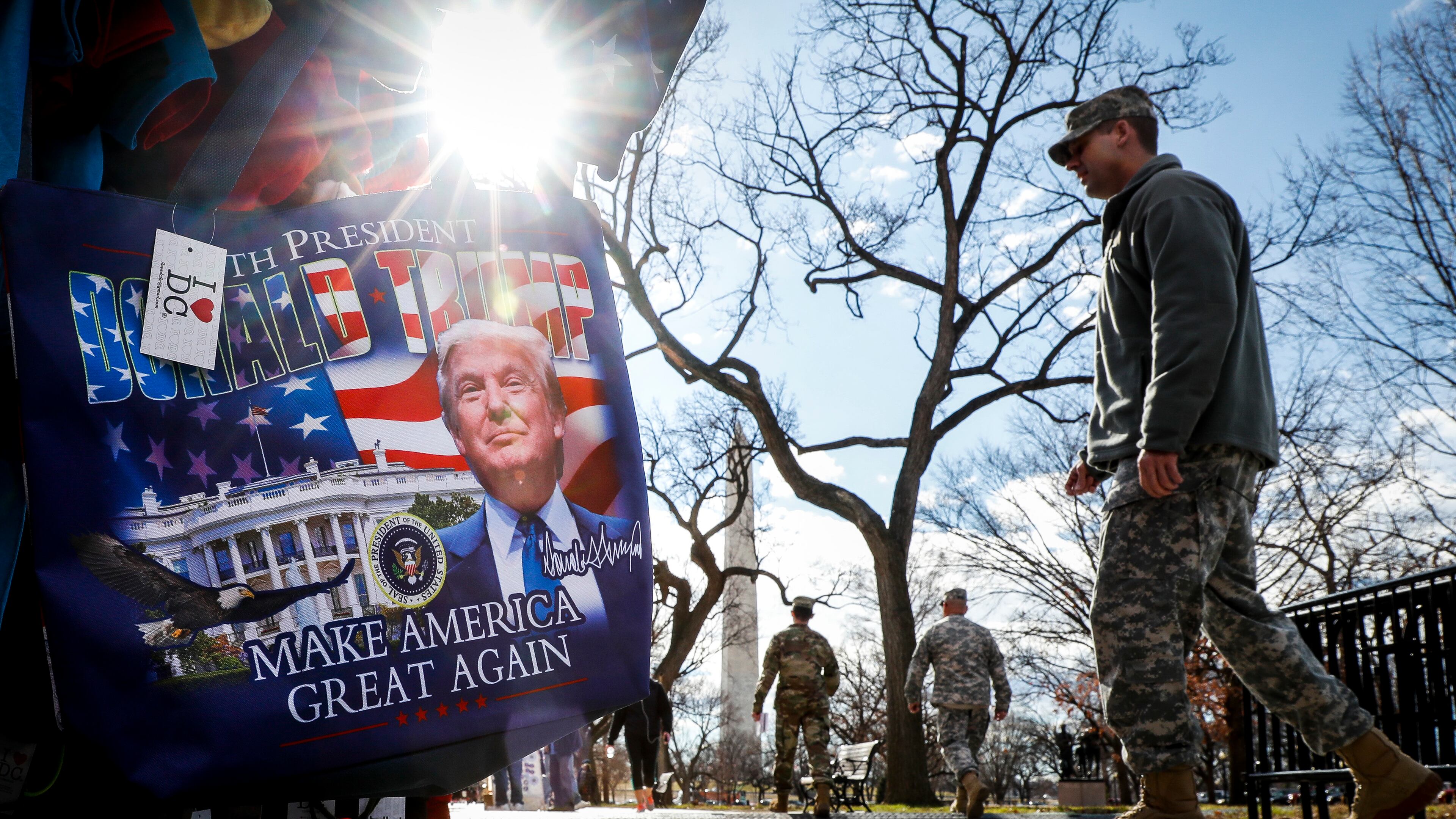 Military personnel walk alongside vendors selling President-elect Donald Trump merchandise on the National Mall in Washington ahead of Friday’s presidential inauguration. (AP Photo/John Minchillo)