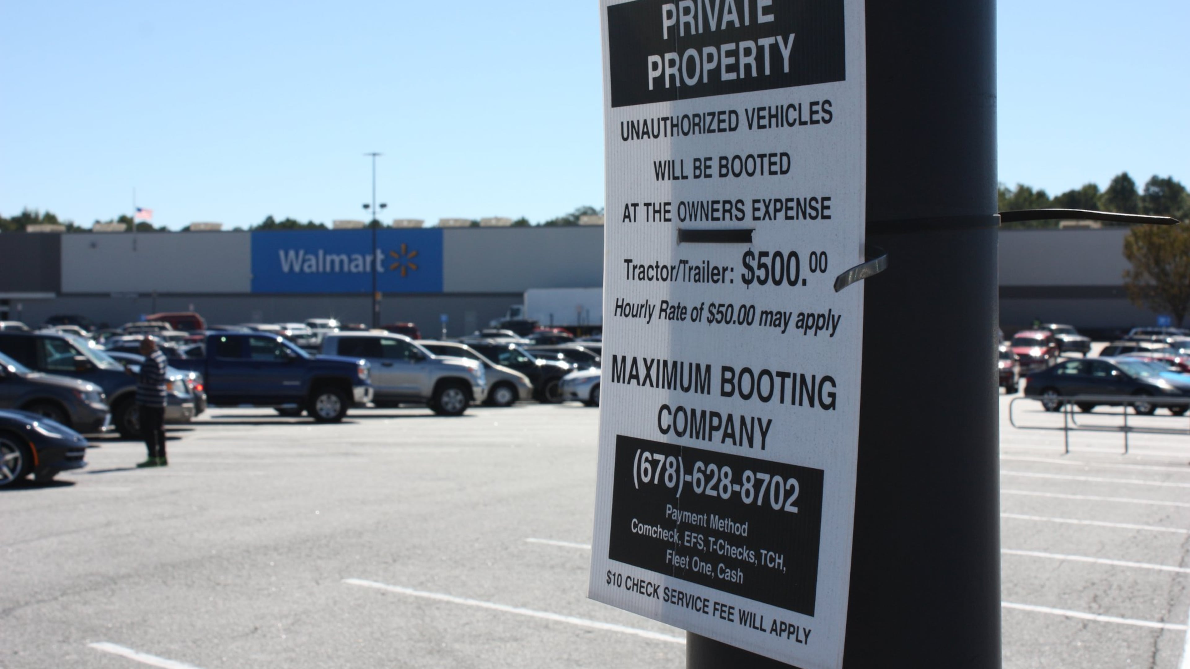 Signs in the Newnan Crossing shopping center in Newnan, Ga., warn owners of “unauthorized vehicles” they are subject to booting.
