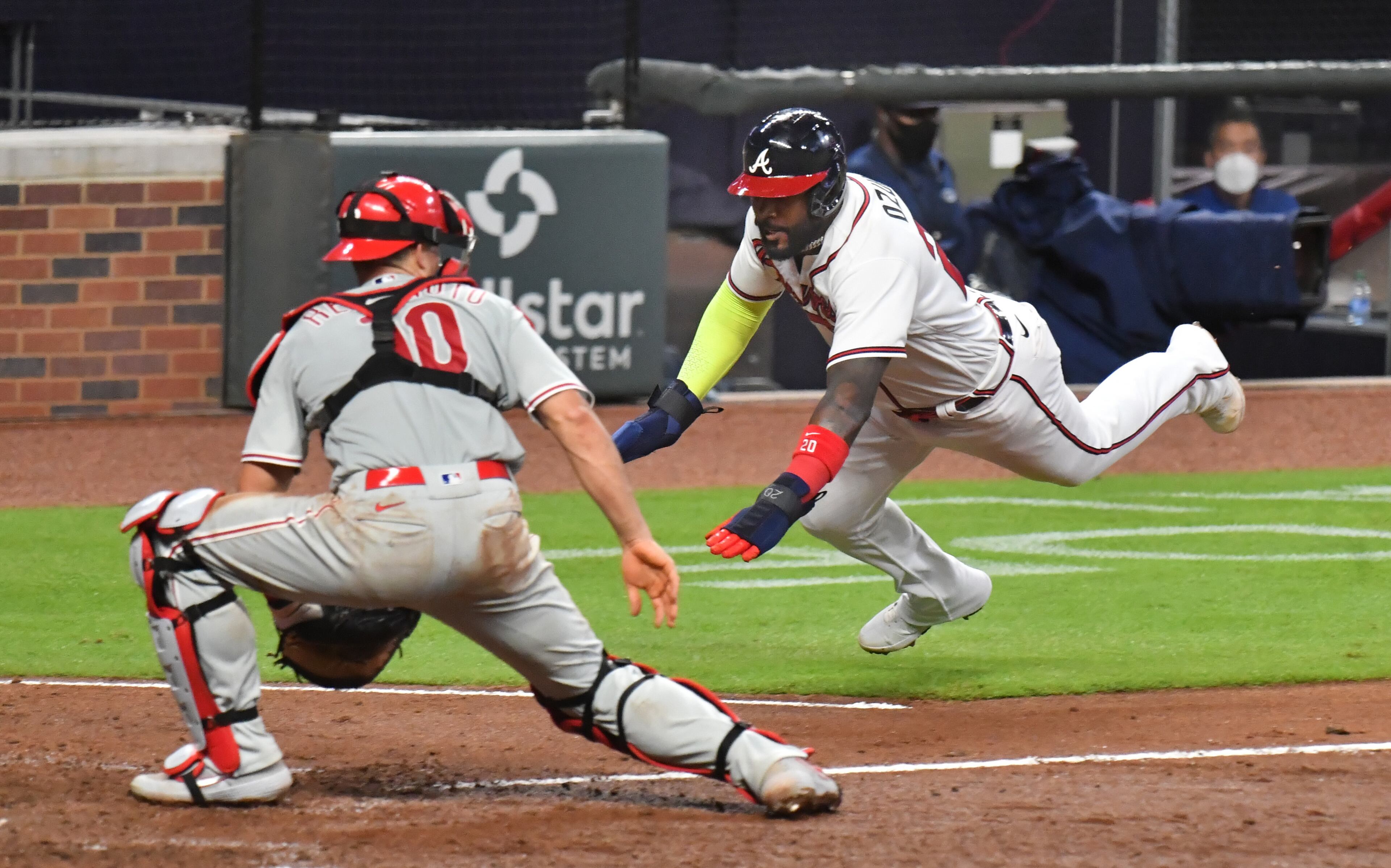 Braves left fielder Marcell Ozuna (20) slides into home plate safely as Philadelphia Phillies catcher J.T. Realmuto (10) waits for the late throw during the 8th inning. (Hyosub Shin / Hyosub.Shin@ajc.com)
