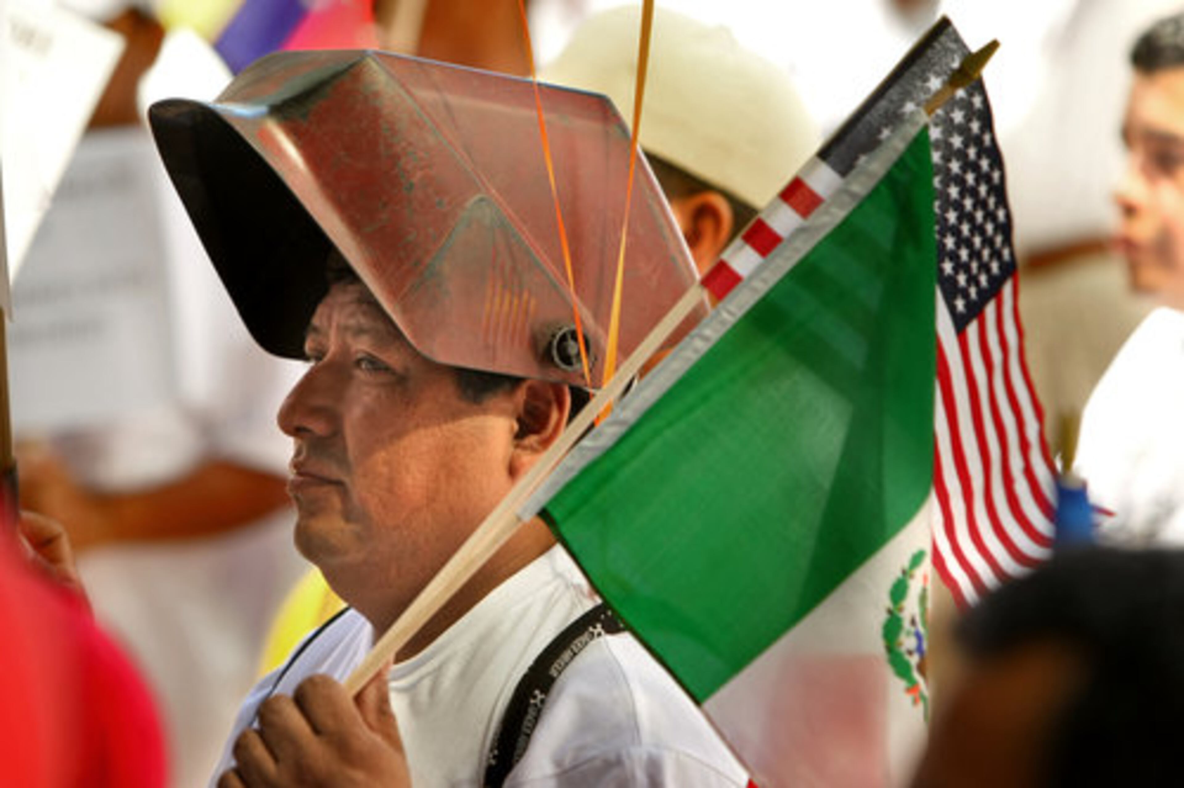 Gustavo Suarez from Smyrna listens to the speakers at Woodruff park carrying flags and his welders mask which he uses for work.