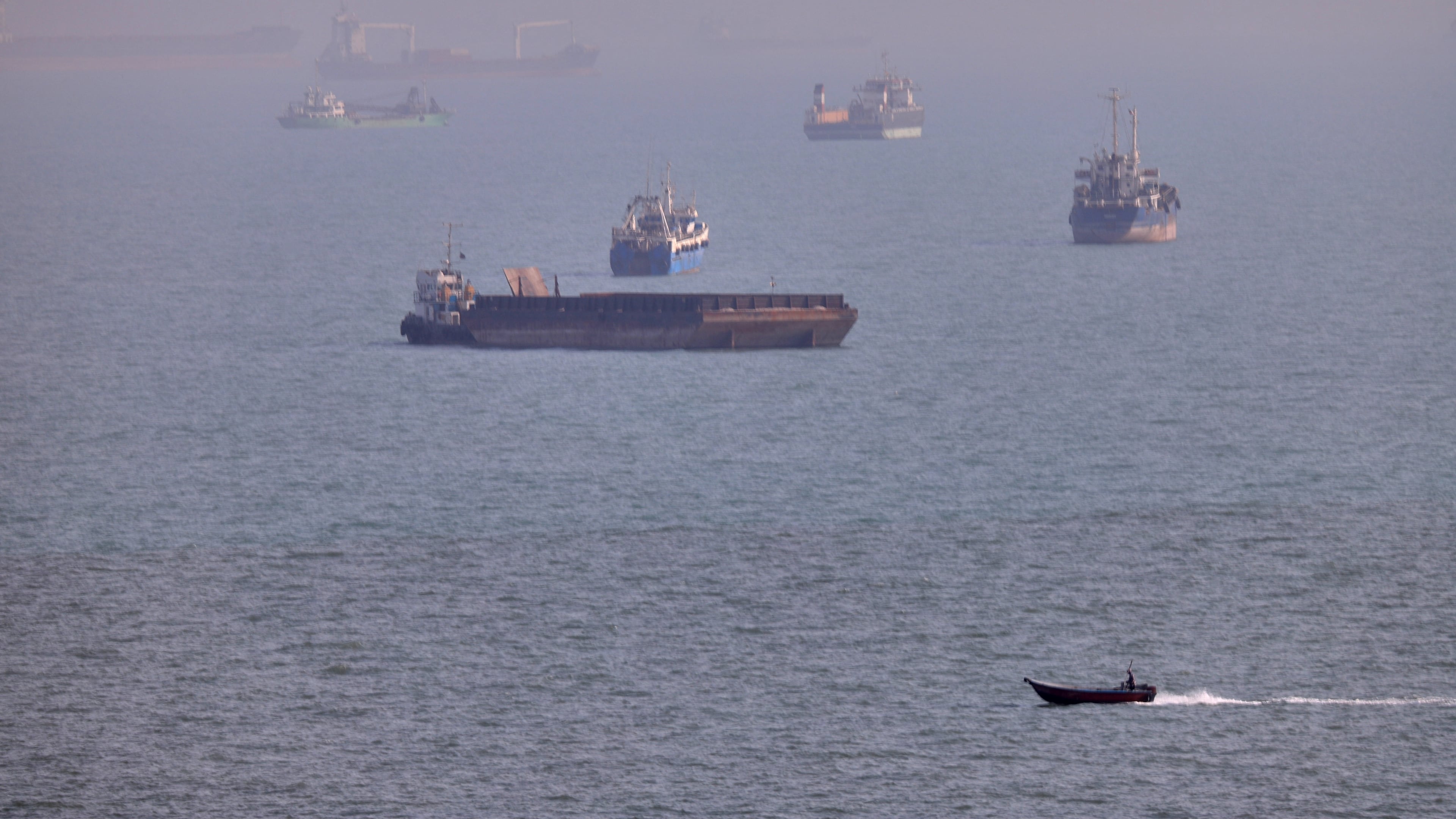 FILE - A small boat sails past cargo ships and other commercial vessels anchored in the Strait of Hormuz off Bandar Abbas, Iran, Wednesday, Aug. 5, 2026. (Amirhosein Khorgooi/ISNA via AP, File)